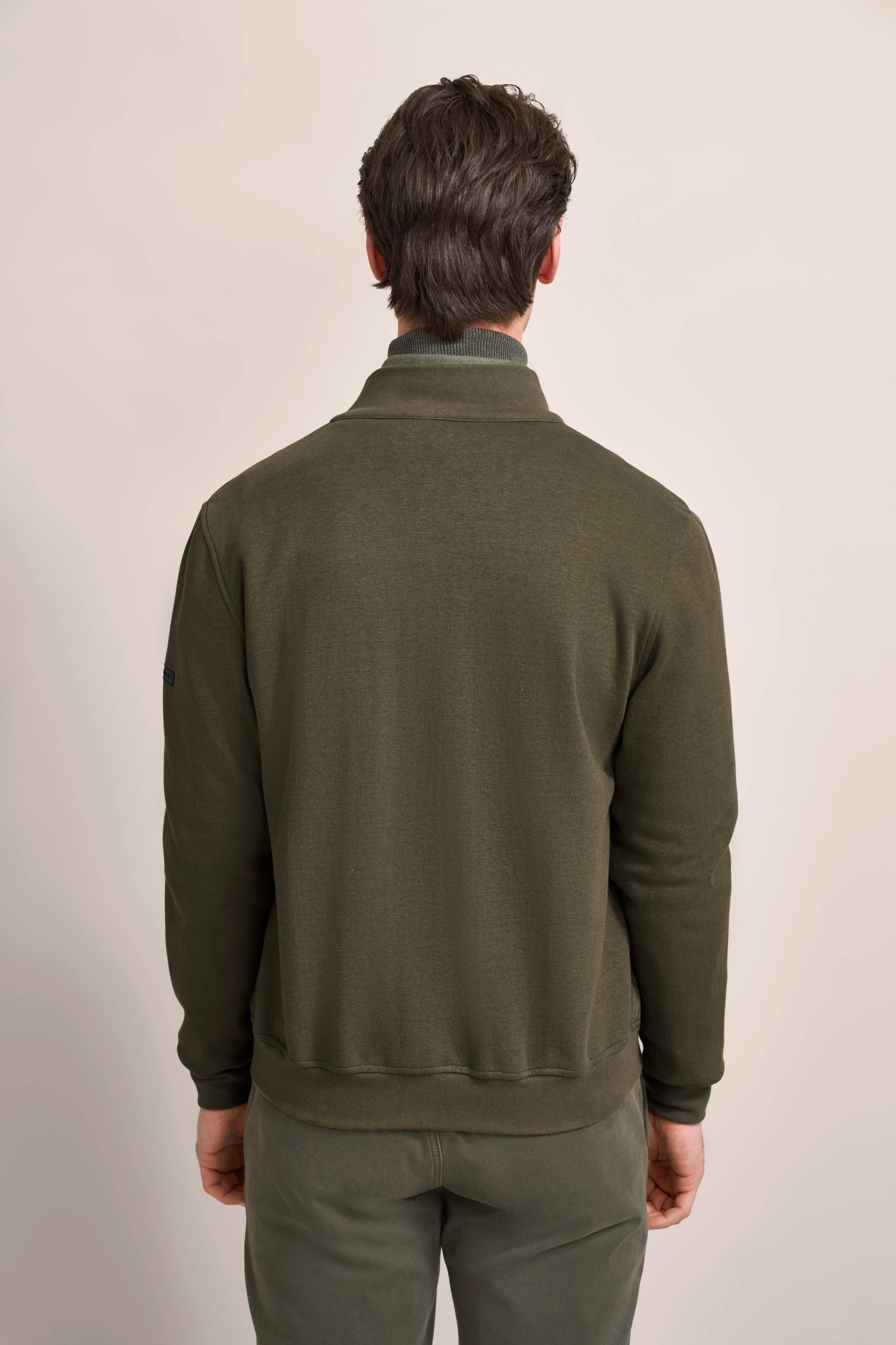 Model in olive bugatti sweatshirt, back view, relaxed pose, timeless style.