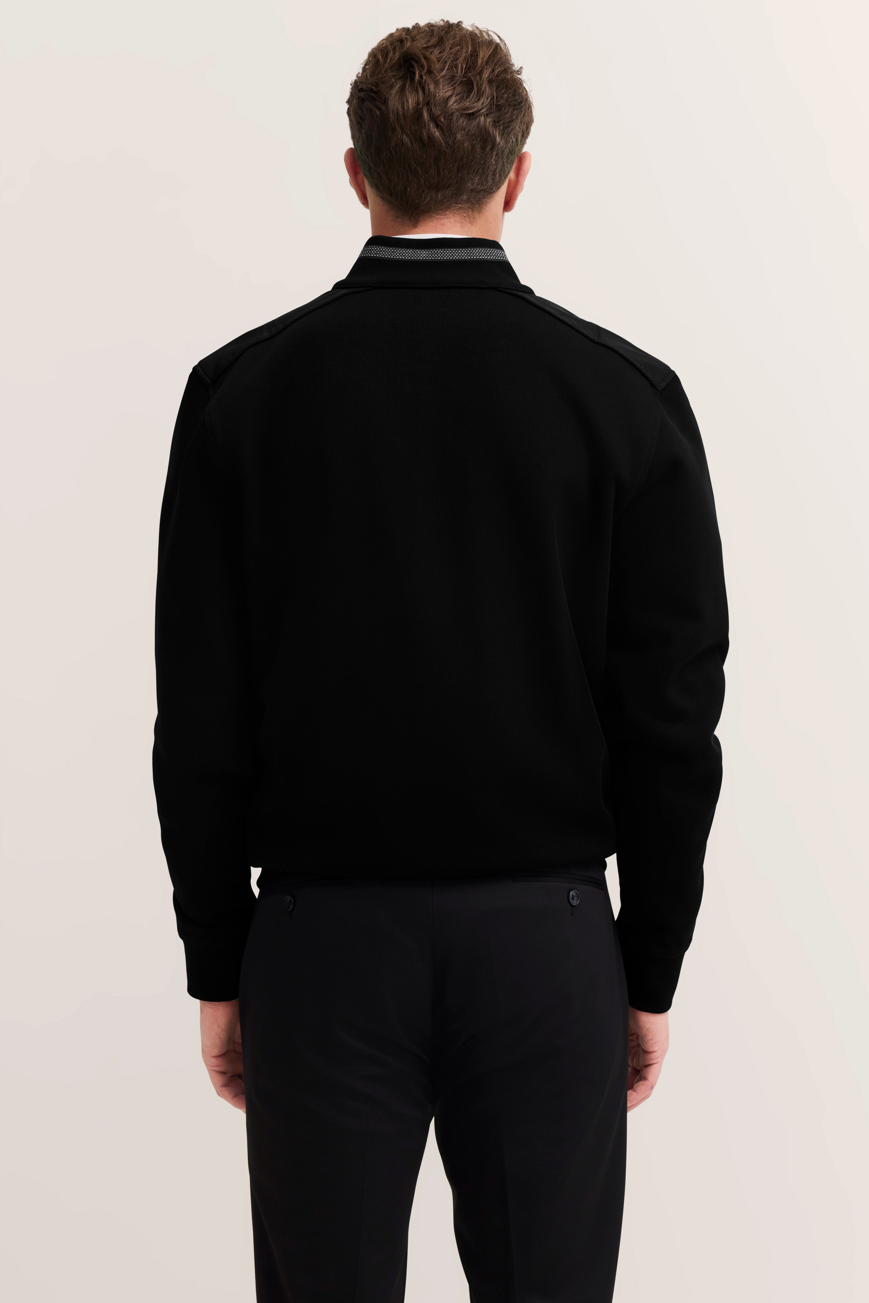 Model zeigt schwarzen bugatti Pullover von hinten, legeres Styling.