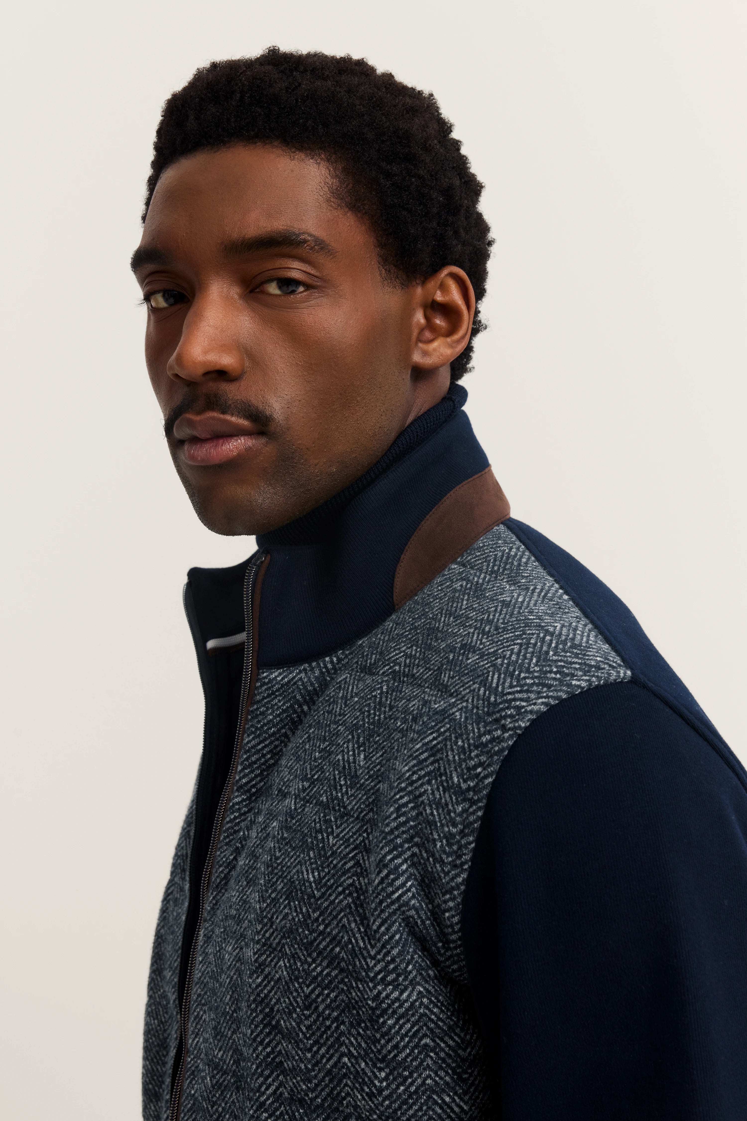 Model in bugatti-Jacke, grau meliert, mit navy Kragen. Büstenbild, entspannter Blick.
