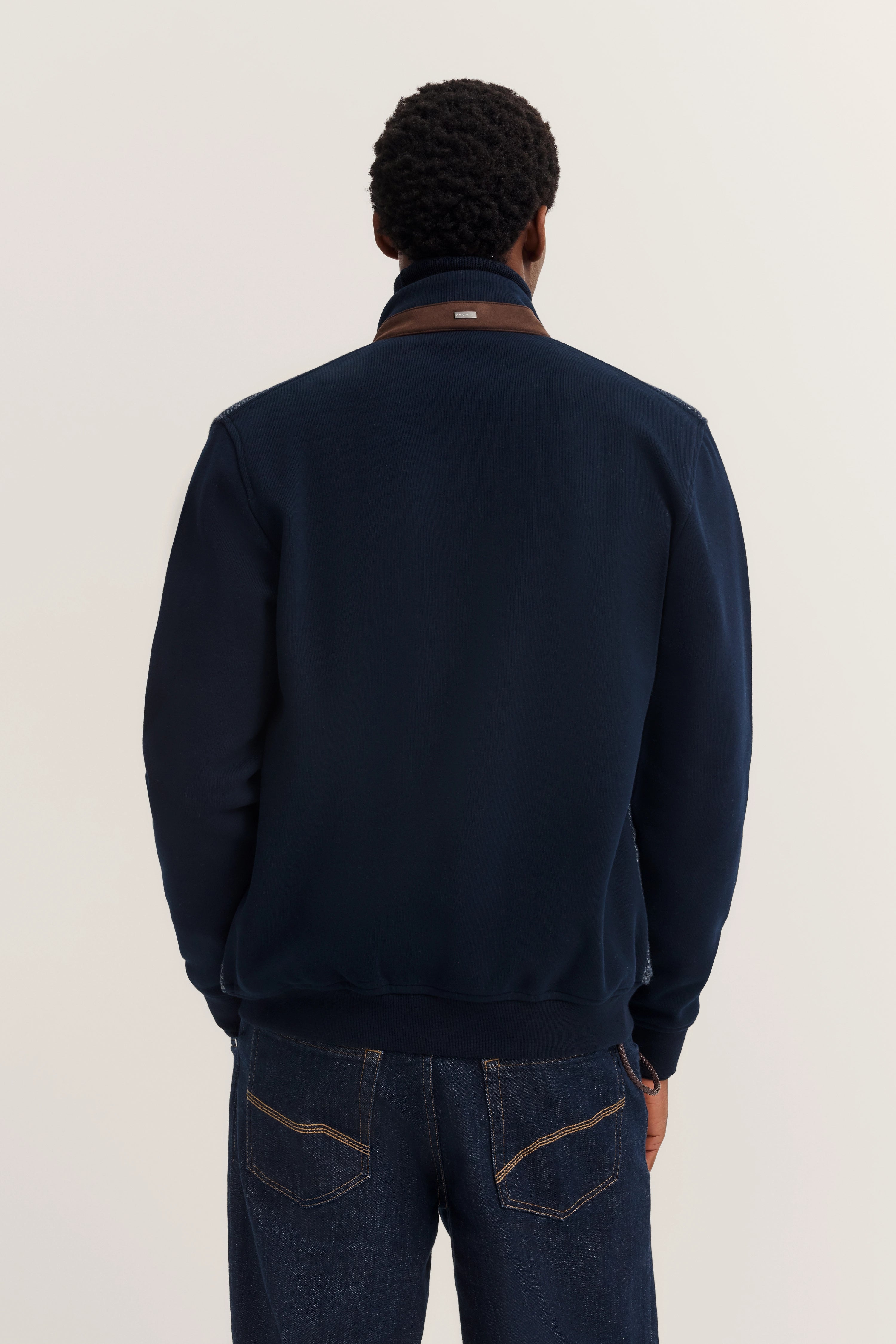 bugatti Modelbild, dunkelblaue Jacke von hinten, lässige Jeans, entspannte Haltung.