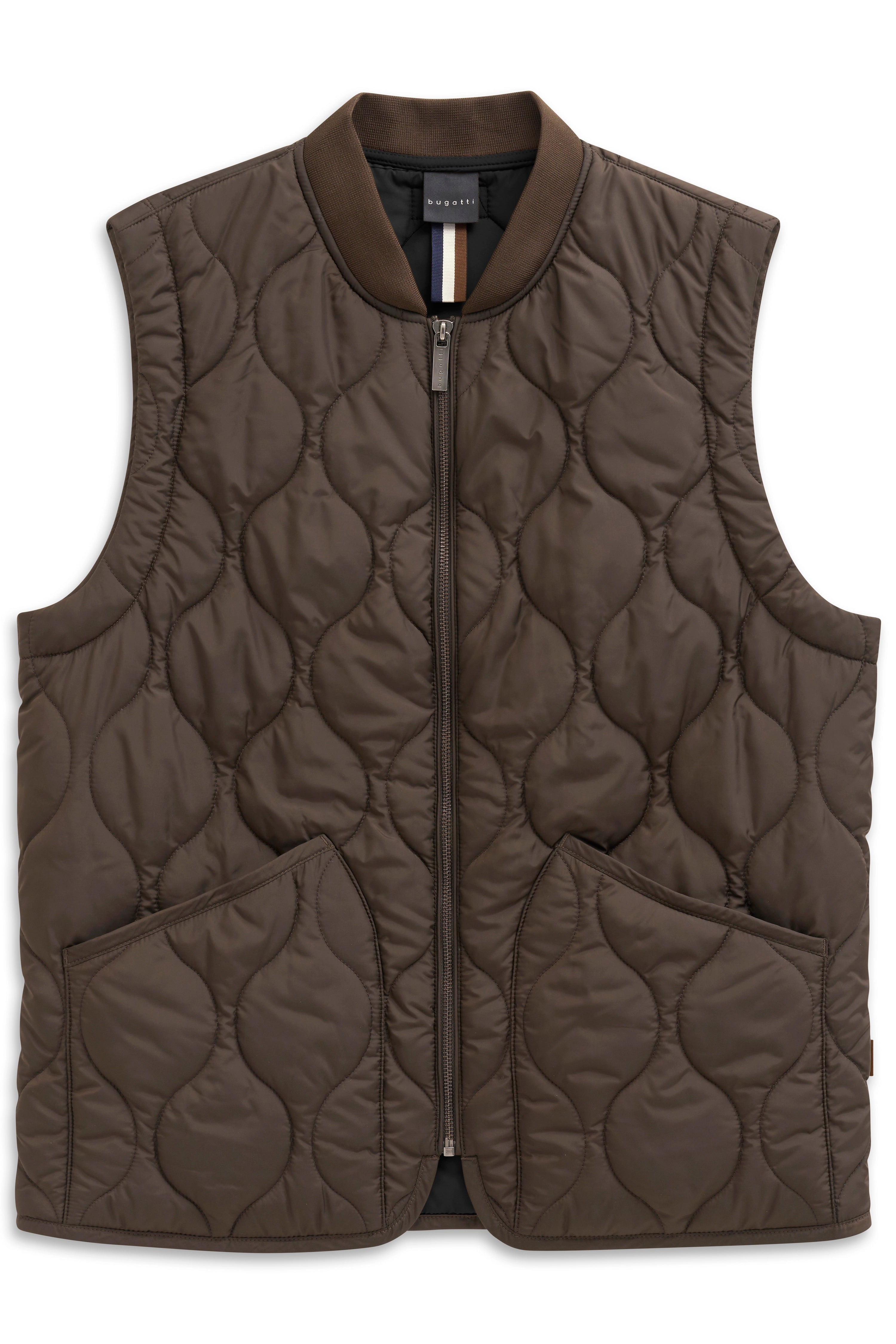 Model in brown quilted vest, knit sweater, and beige pants. Casual pose, hands in pockets.