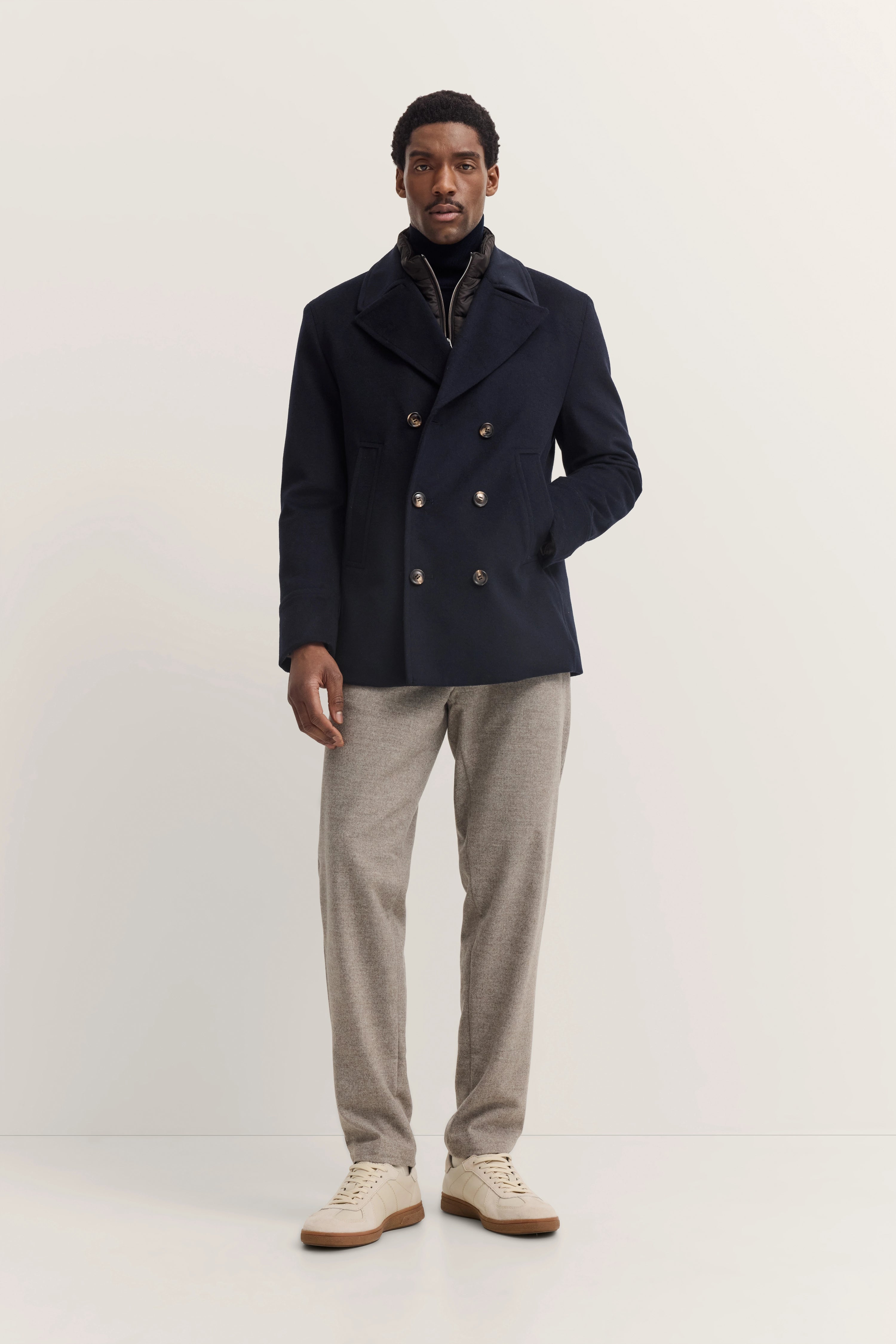 Model met bugatti marineblauwe jas, grijze broek, beige sneaker