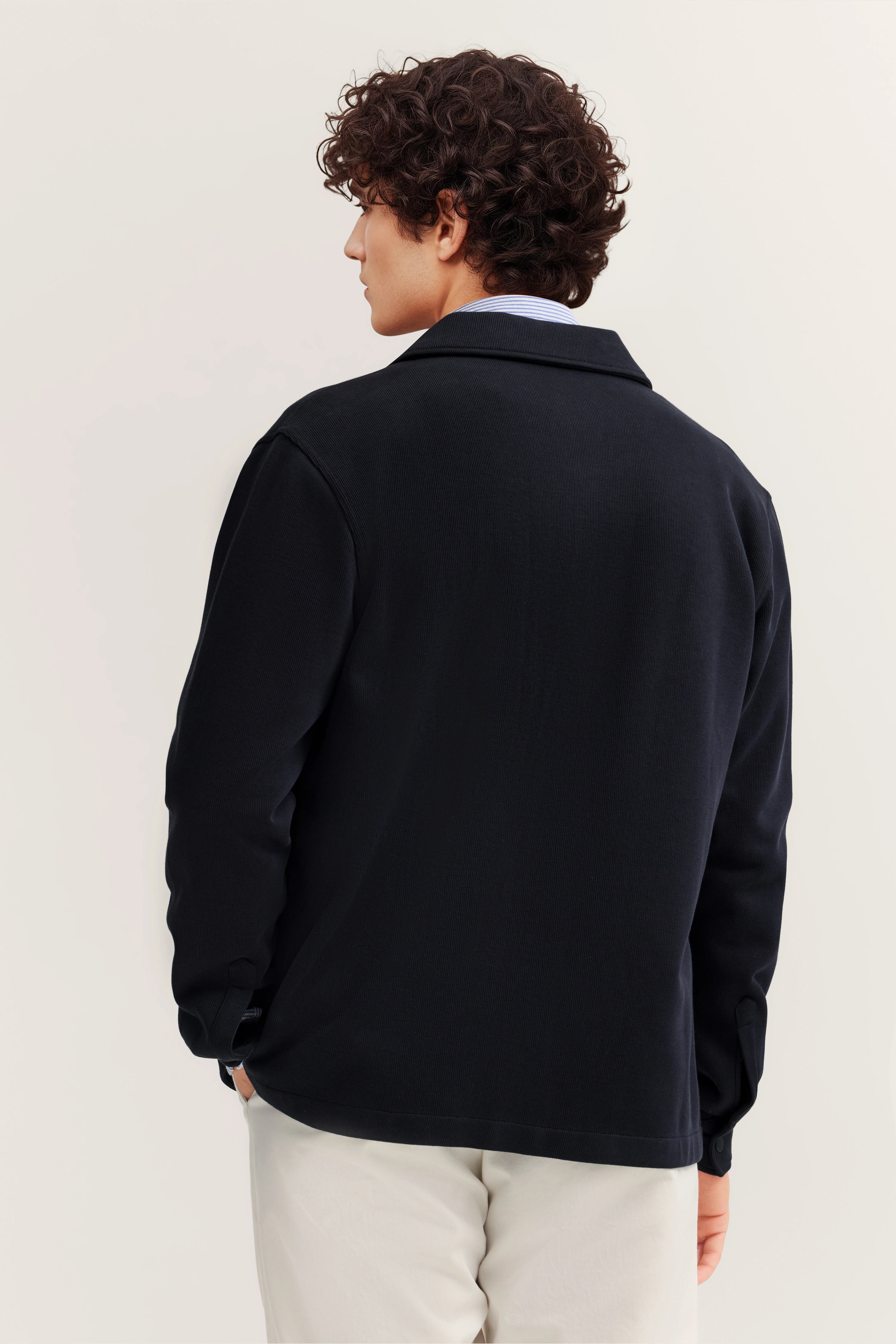 bugatti Modell in schwarzem Blazer, legerer Stil, Rückansicht, kombiniert mit beiger Hose.