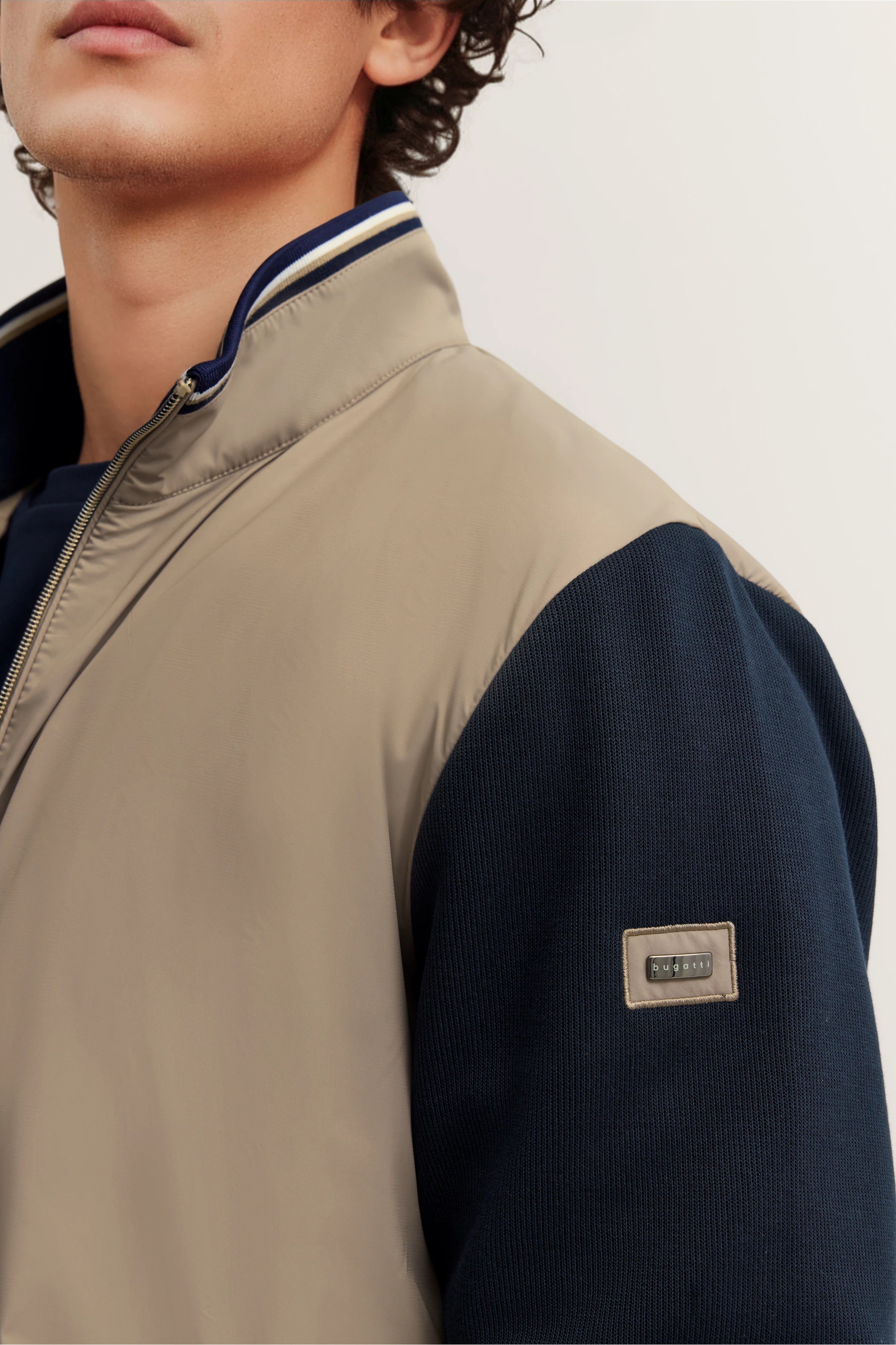 Beigefarbene und dunkelblaue bugatti Jacke, Close-up auf Stoffdetails, Modelbild.