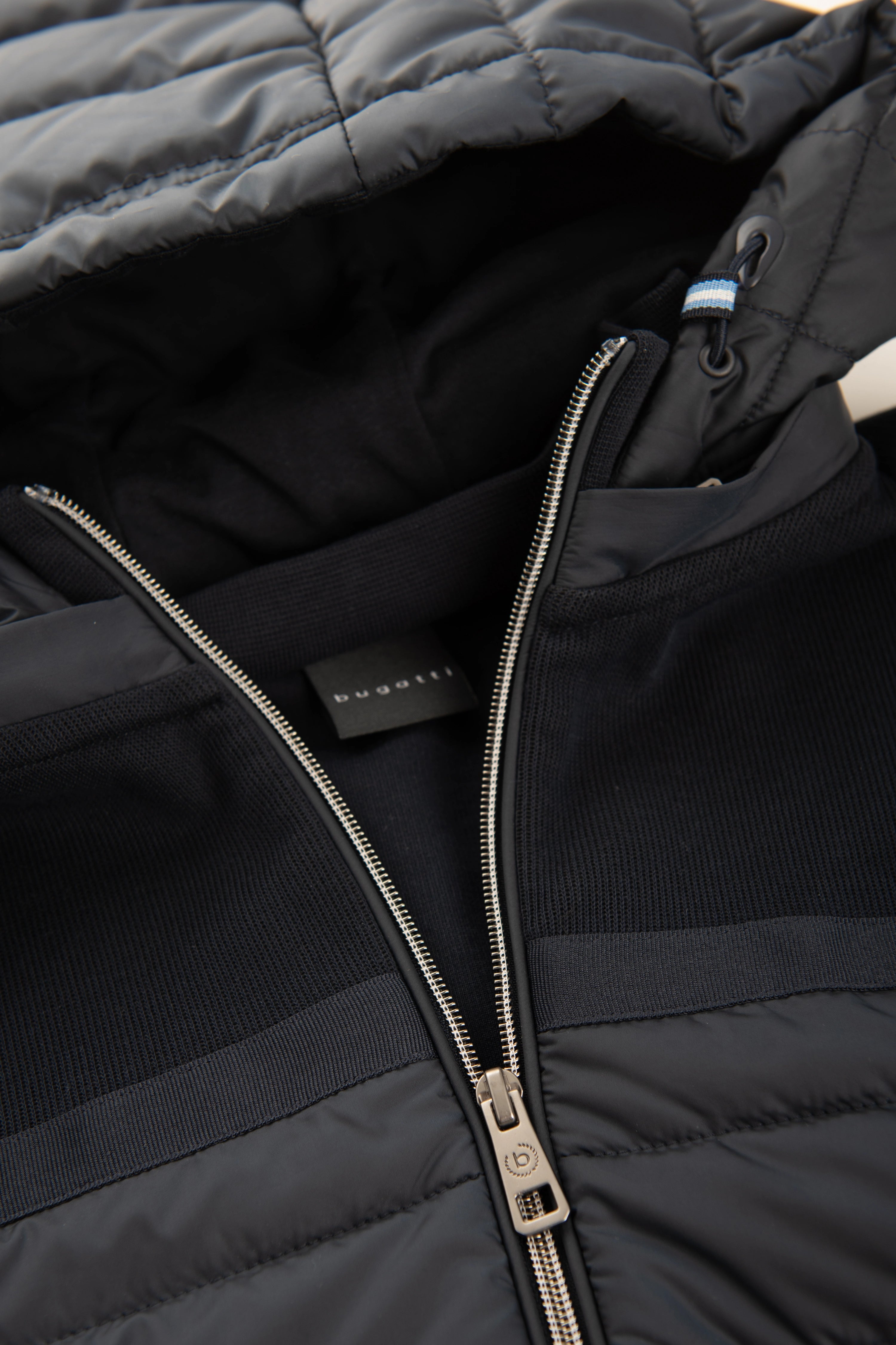 bugatti schwarze Jacke mit gestepptem Design, Detailansicht des Kragens und Reißverschlusses, Büstenbild.