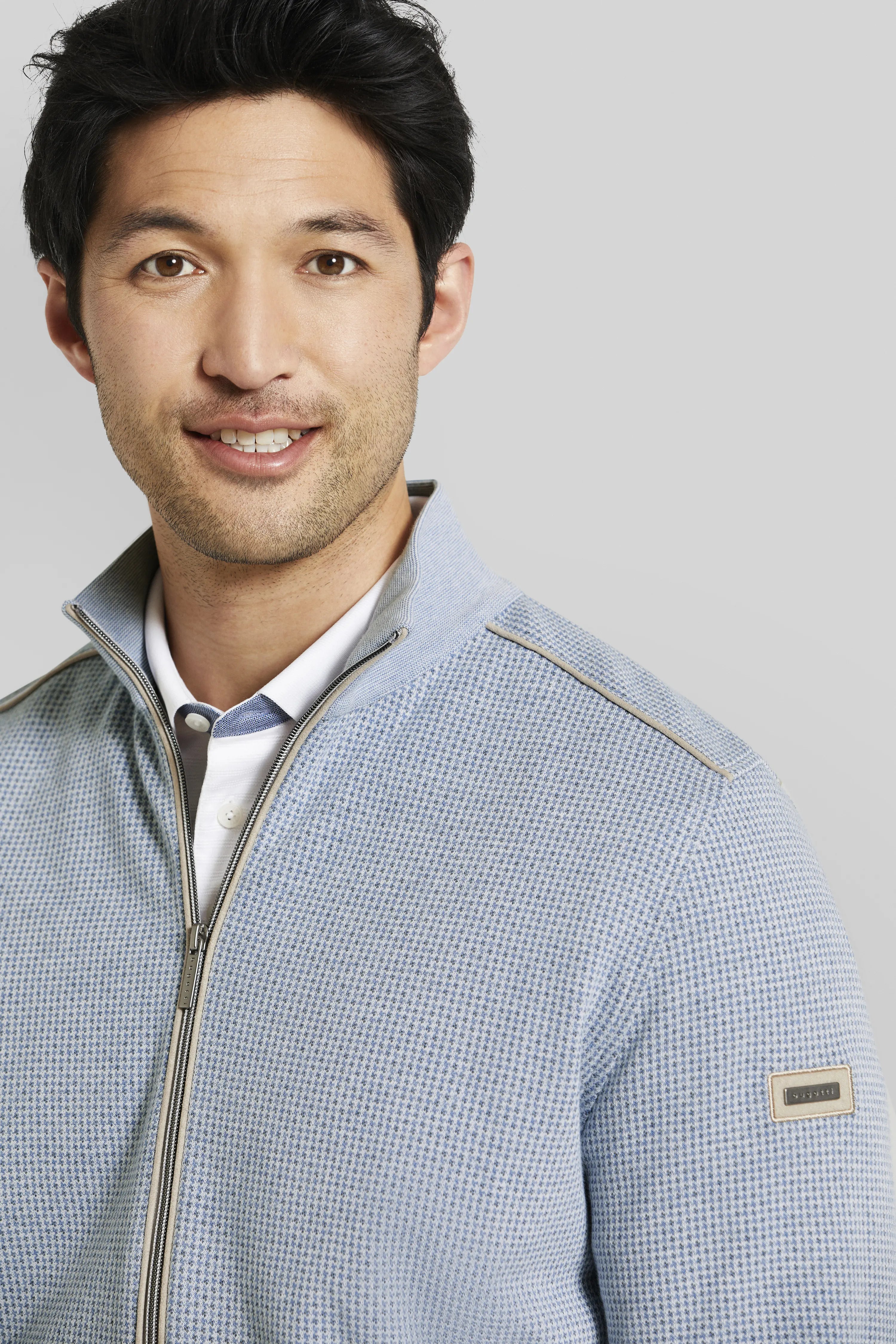 Blue bugatti top with zipper, fine pattern, model image, casual pose.