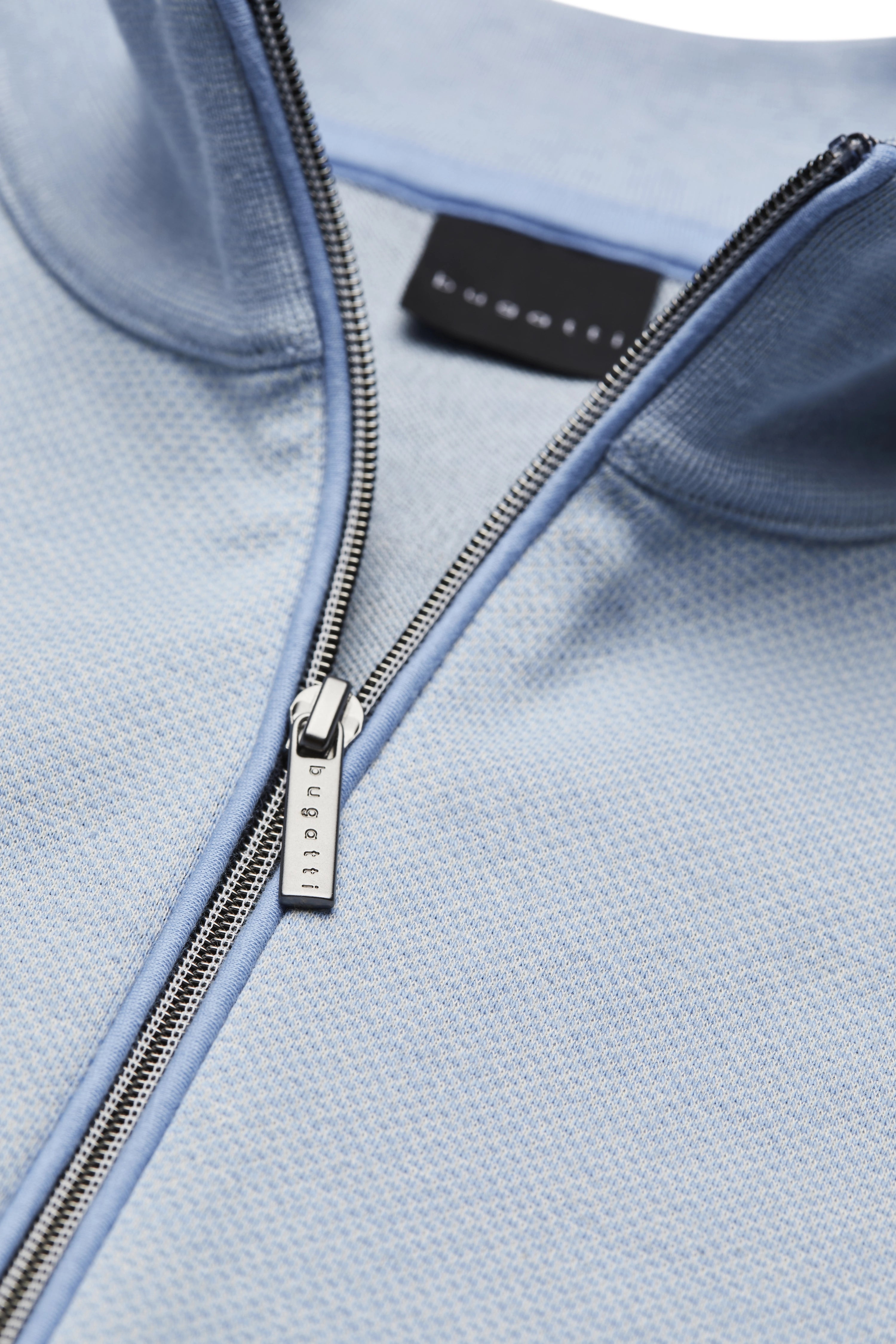 Model in light blue bugatti top, portrait, relaxed, confident expression.