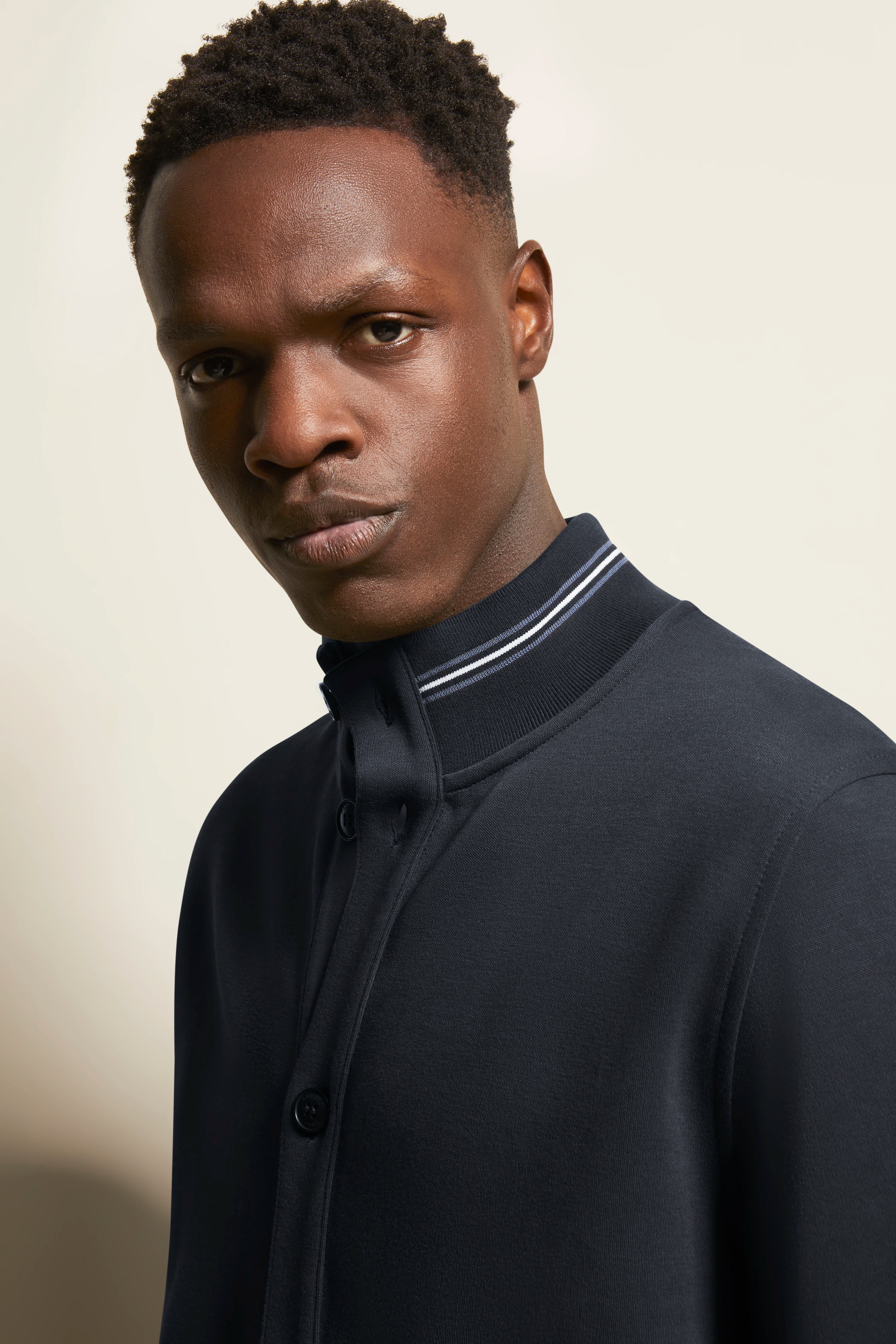 Model in navy bugatti jacket with striped collar, bust view, stylish and elegant.