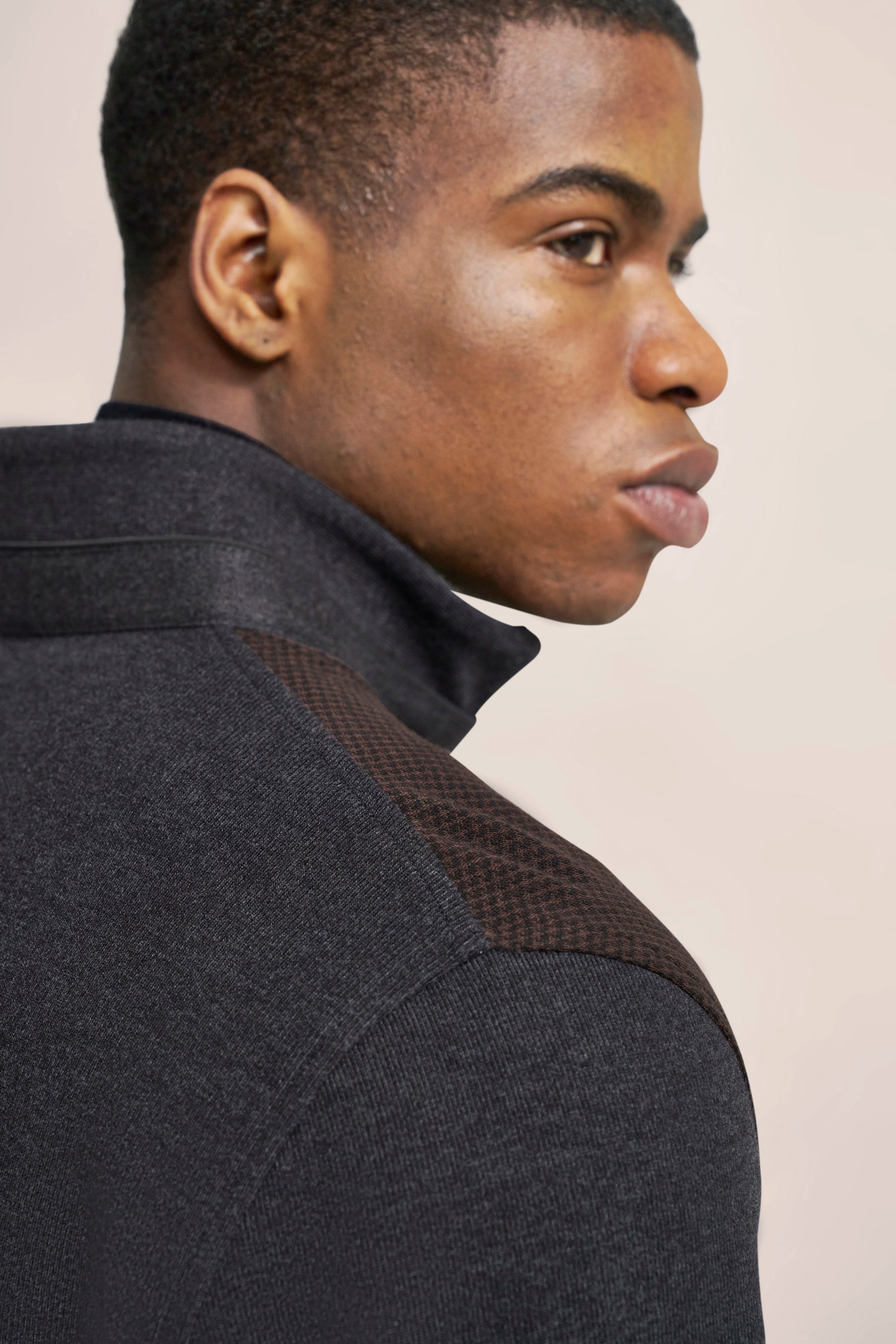 Bust of a man in a gray bugatti sweater with brown shoulder design.
