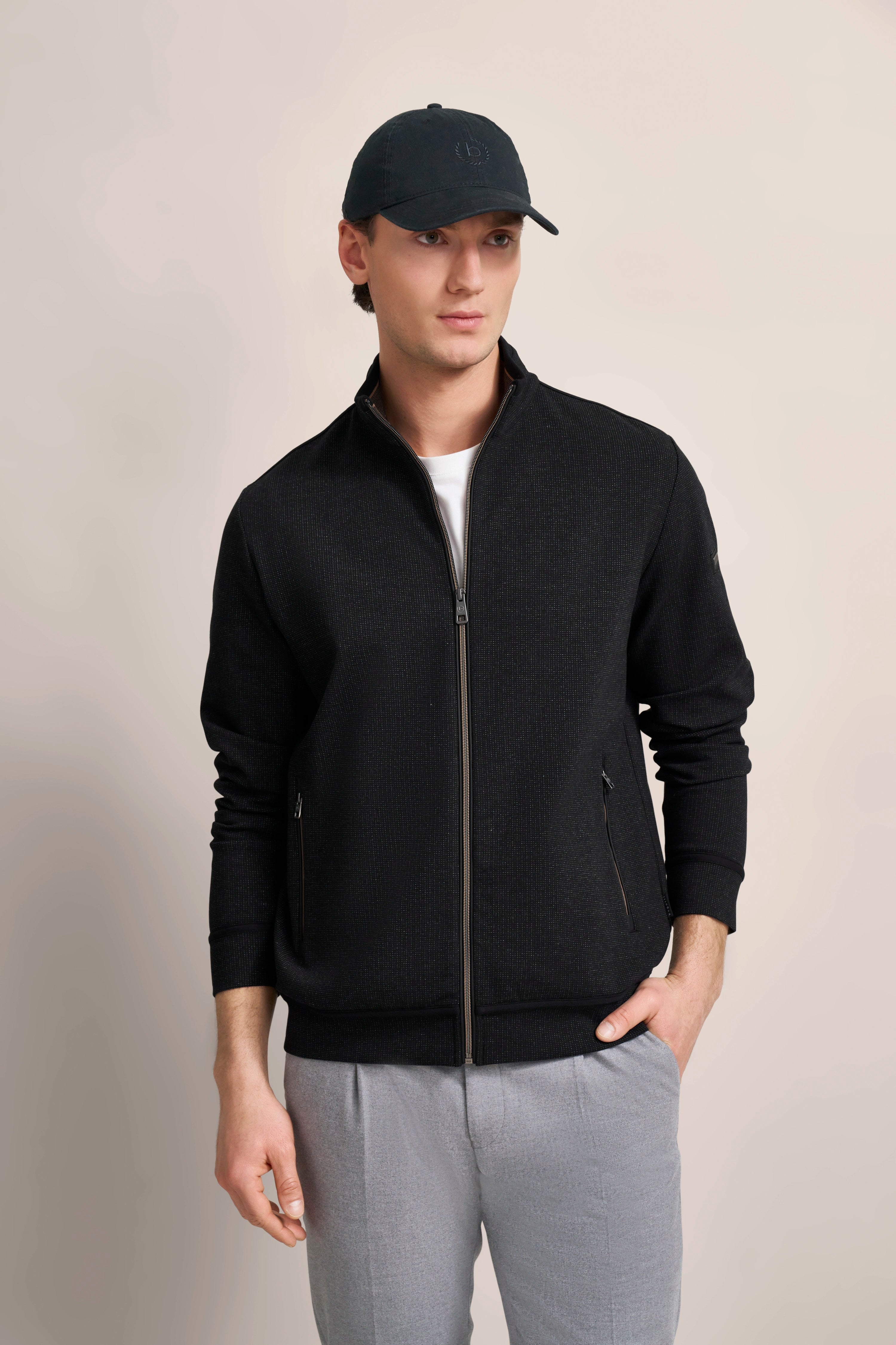 bugatti Model in schwarzer Jacke und grauer Hose, legeres Posing mit Basecap.