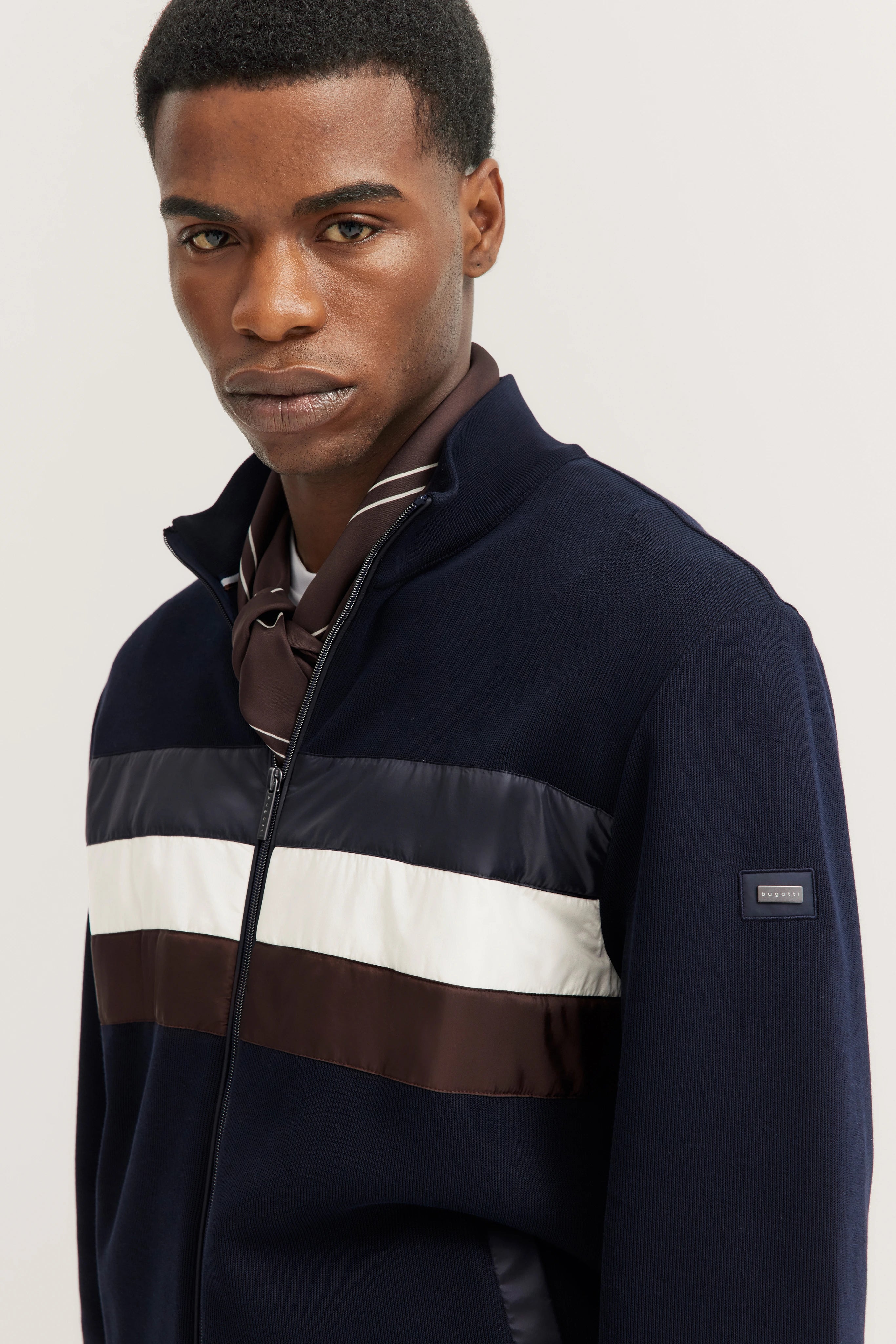 Model in bugatti blue sweater with brown and white stripes, elegant pose.