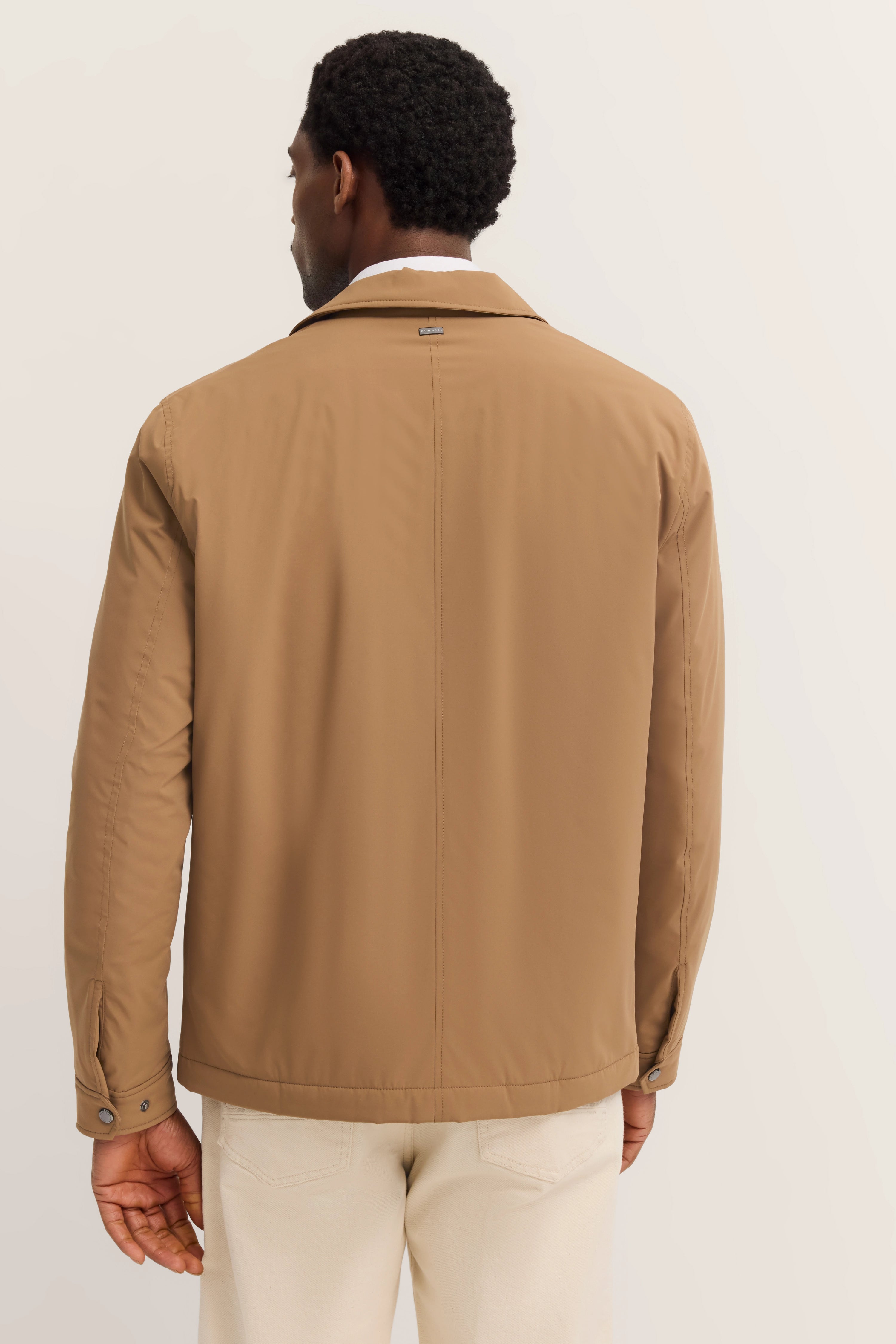 Bugatti herenjack in beige, achterkant, gedragen door model in ontspannen houding, stijlvol en tijdloos.