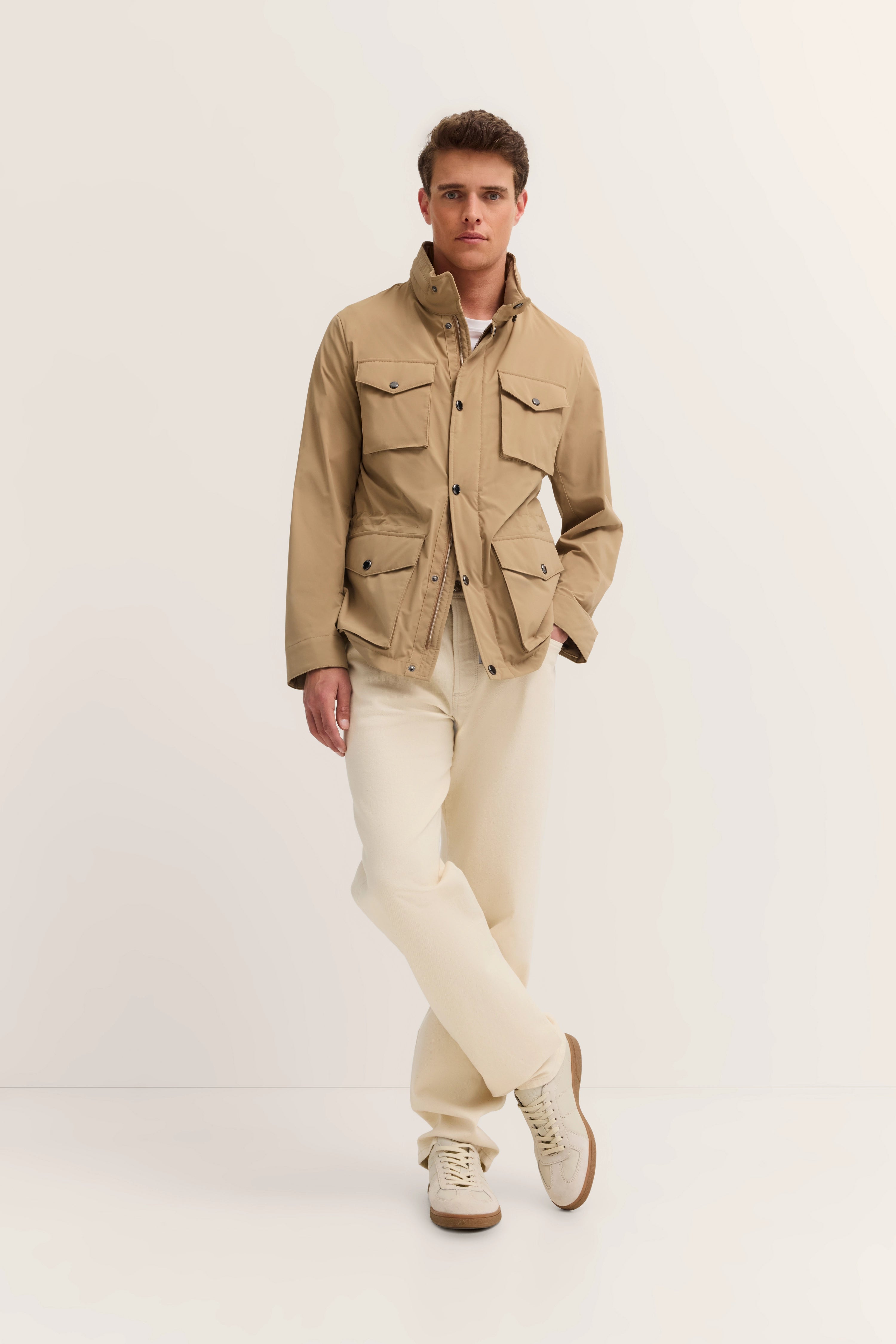 Model in beige bugatti jacket, cream pants, casual pose.