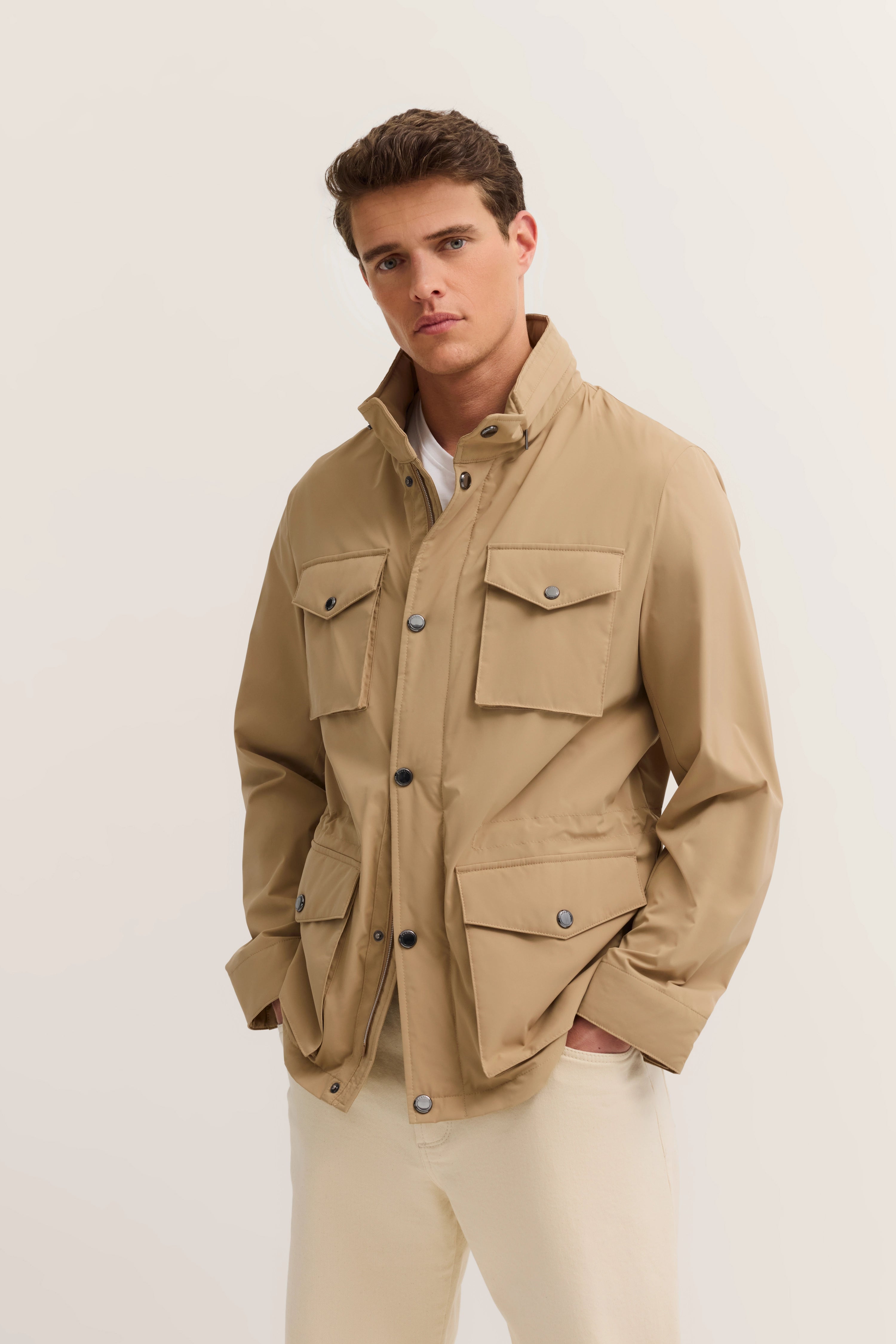 Beige bugatti jacket with pockets, model pose, casual style, white pants.