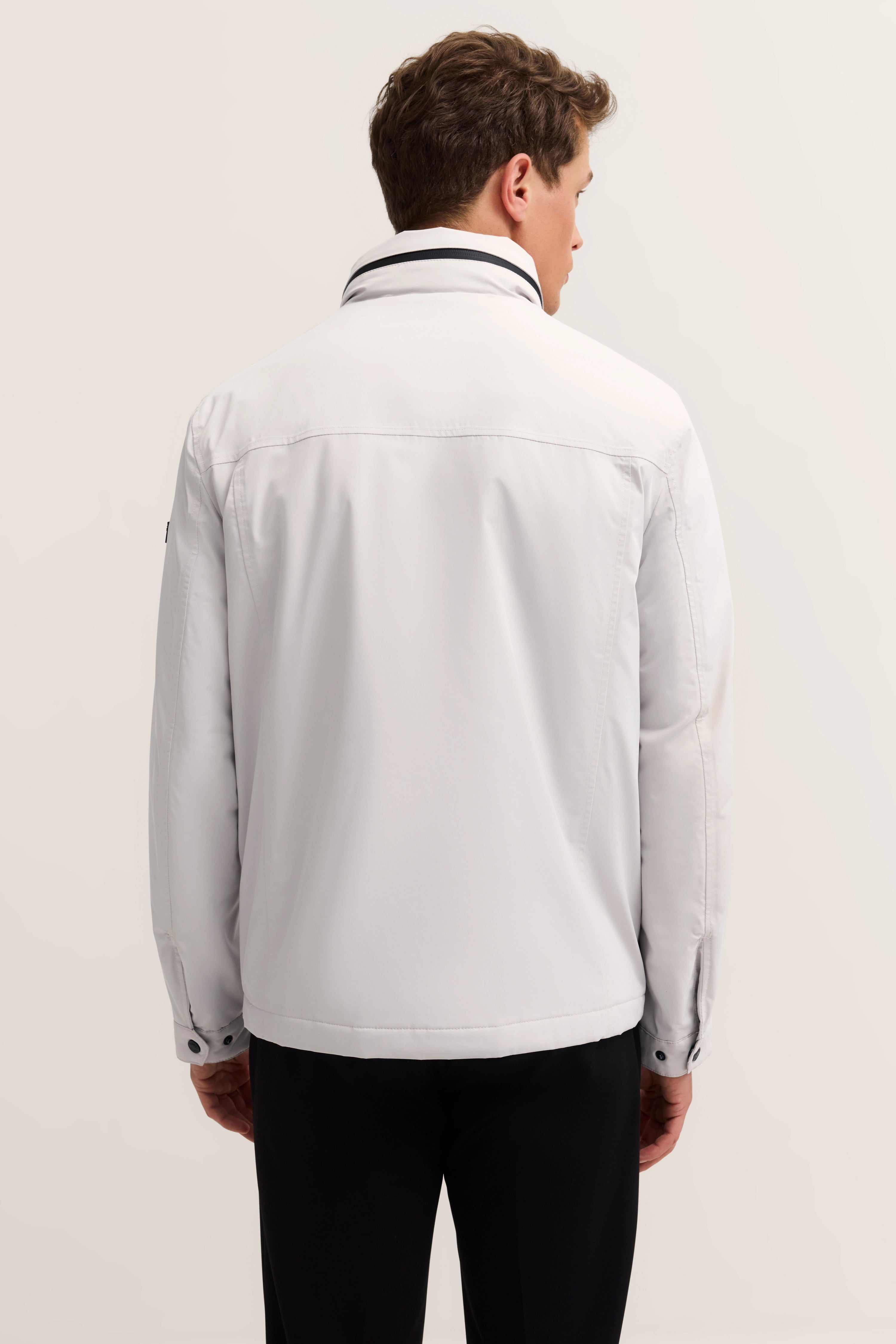 White bugatti jacket, back view, model pose, relaxed, black pants.
