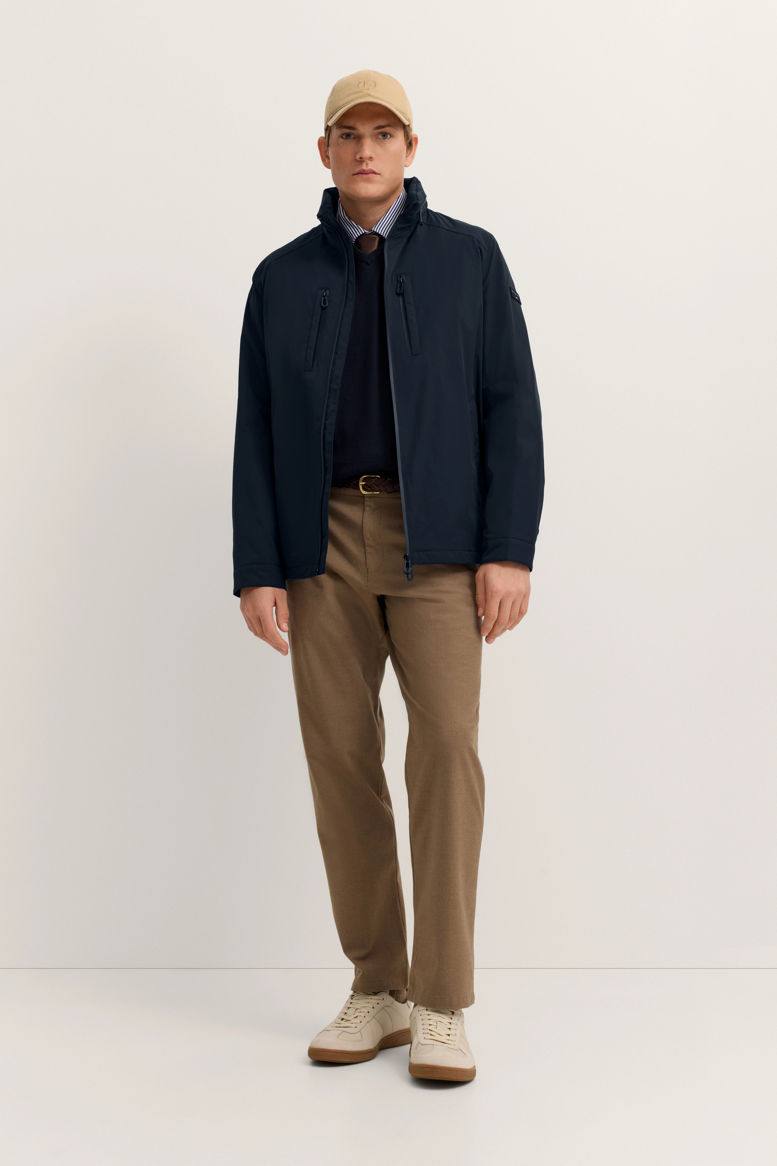 Rückansicht eines Models mit dunkelblauer bugatti Jacke und beige Hose, lässig posierend.