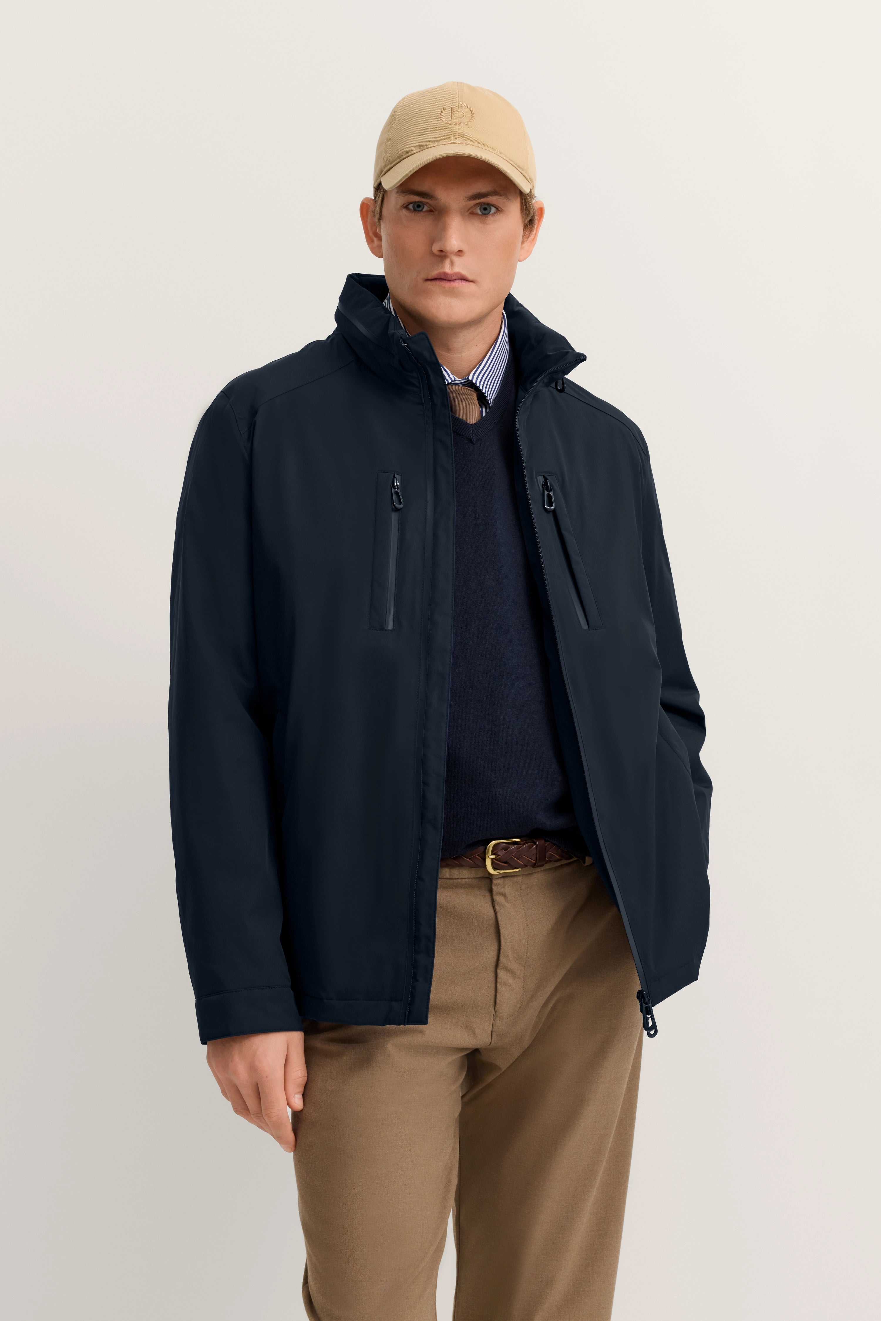 Model in dunkelblauer bugatti-Jacke, navy Pullover, Hemd, beige Hose, Kappe