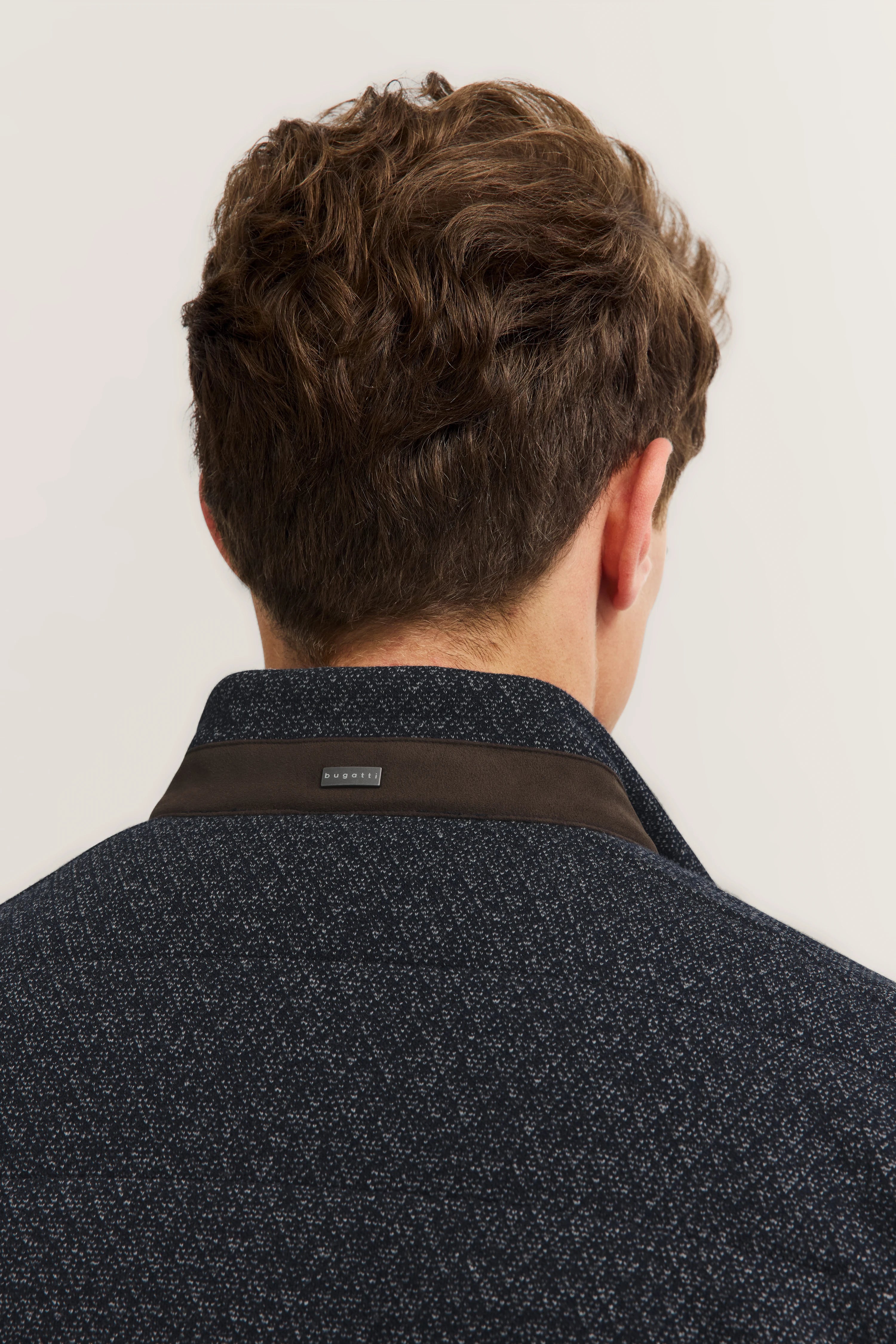 Back view of man in bugatti shirt with dark pattern and brown collar.