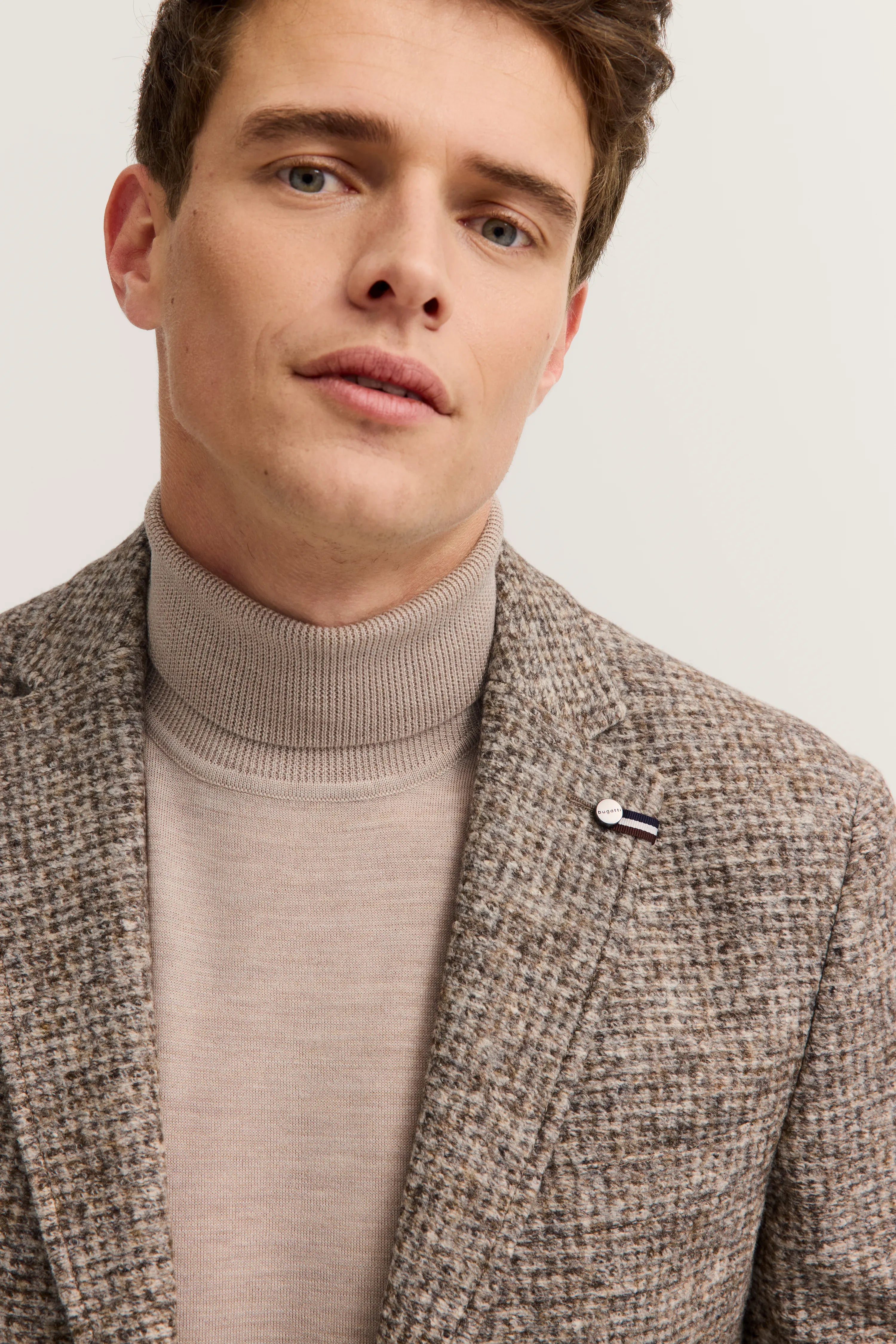 Büstenbild mit beigem Rollkragenpullover und kariertem Sakko von bugatti.