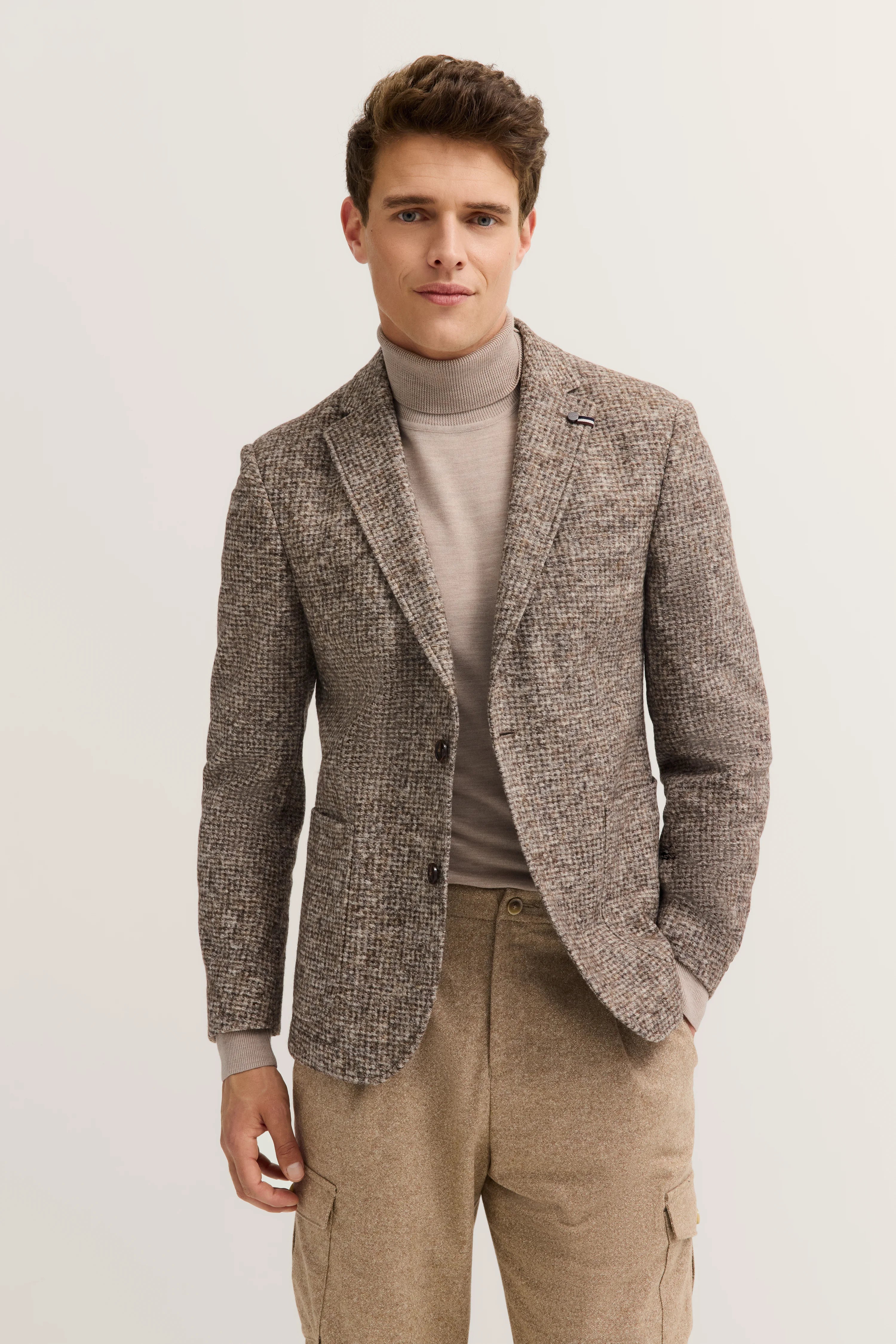 Model in braunem Tweed-Blazer und Rollkragenpullover, beige Hose, entspanntes Posing.