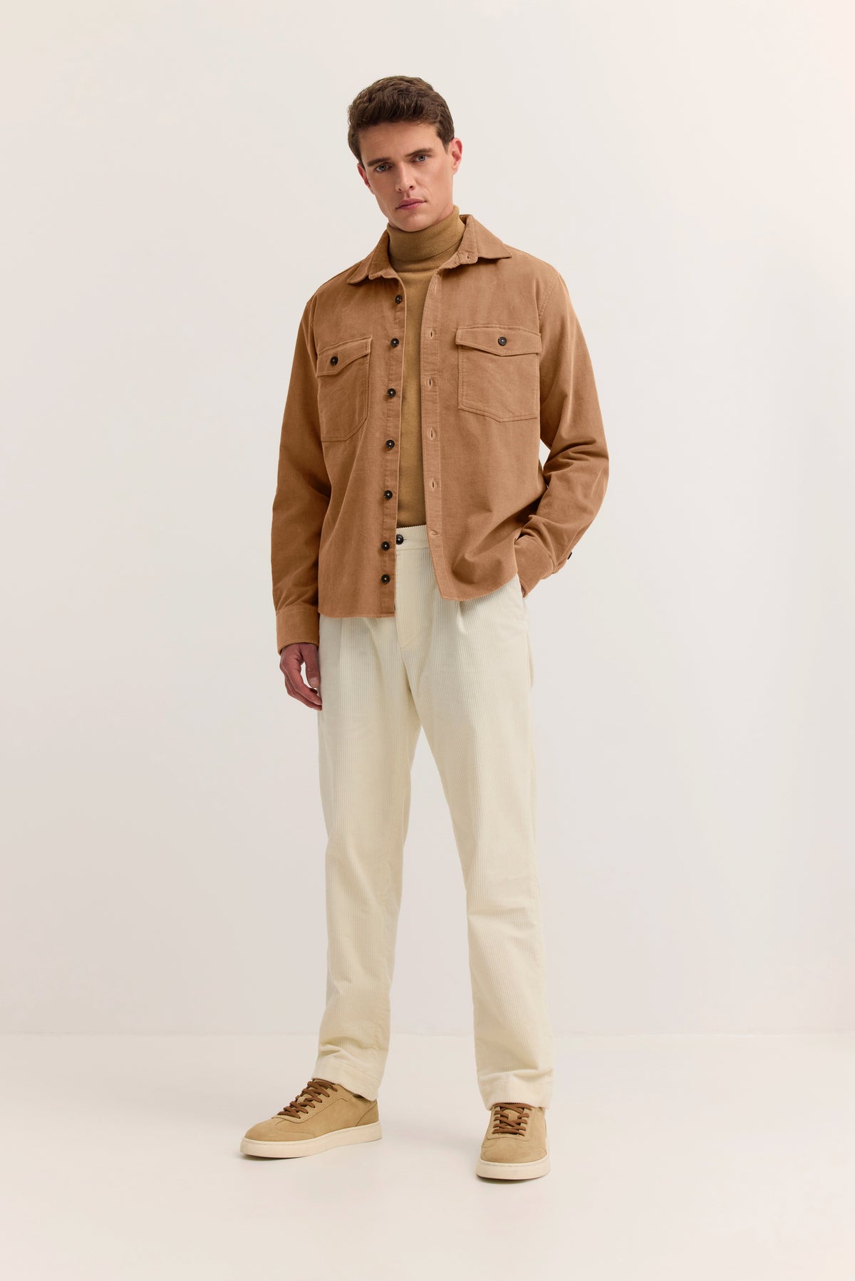 Model in beige Cordjacke und Rollkragenpullover, Brustbild, blickt zur Seite.