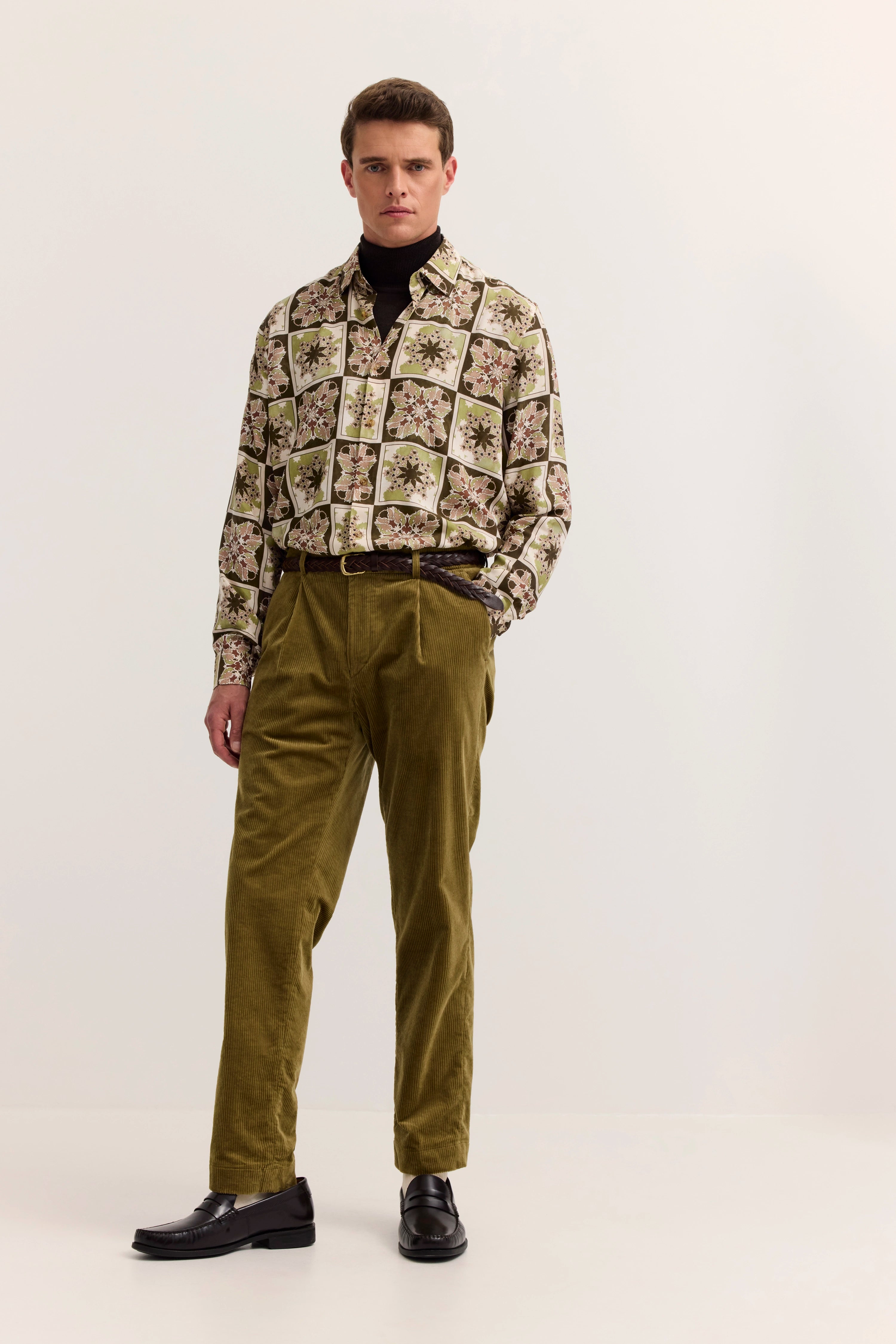 "Modelbild: Mann in gemustertem Hemd und olivgrüner Hose, stehendes Posing, bugatti Stil."