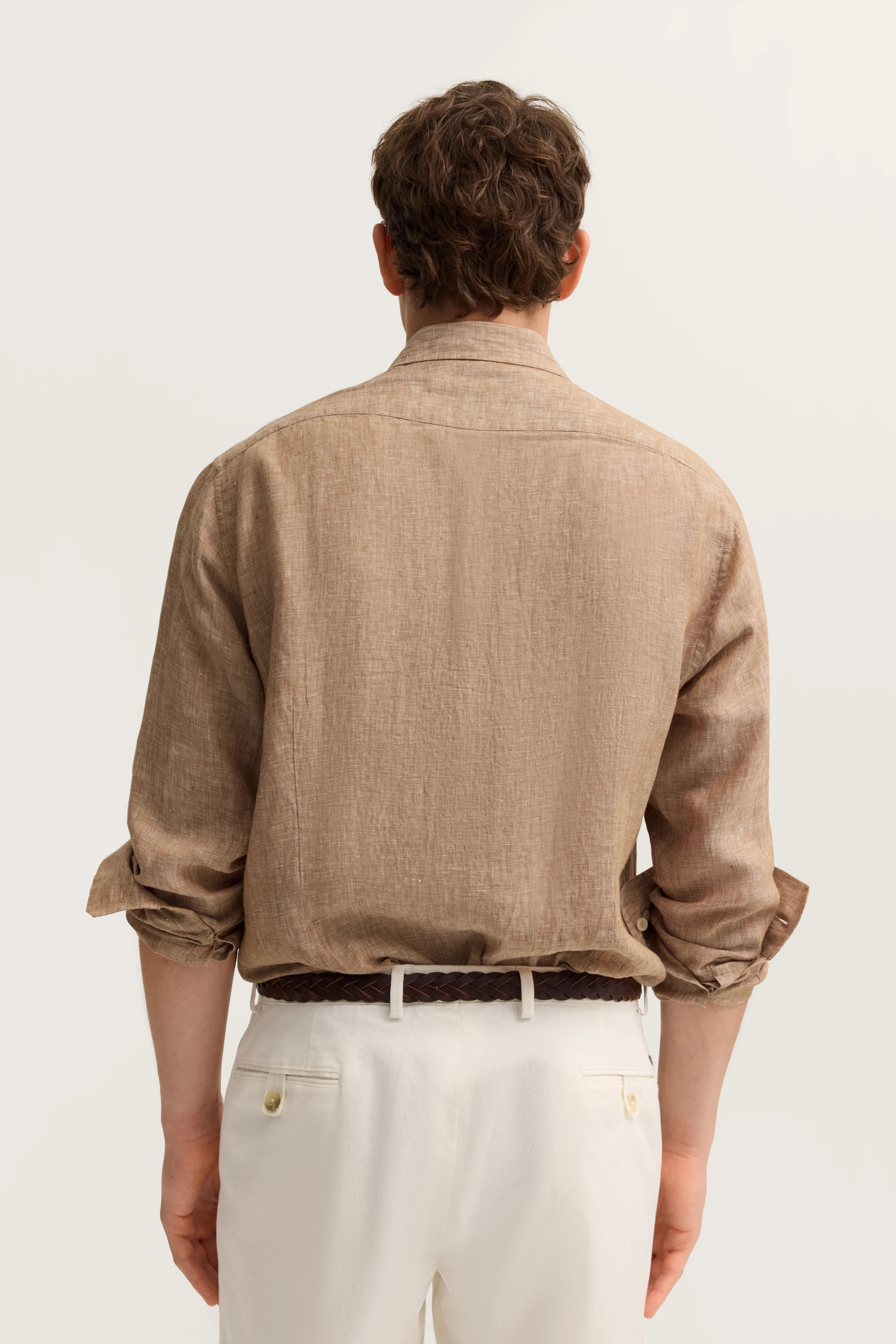 Beige bugatti Hemd und weiße Hose, Rückansicht, legeres Modelbild, entspannte Haltung.