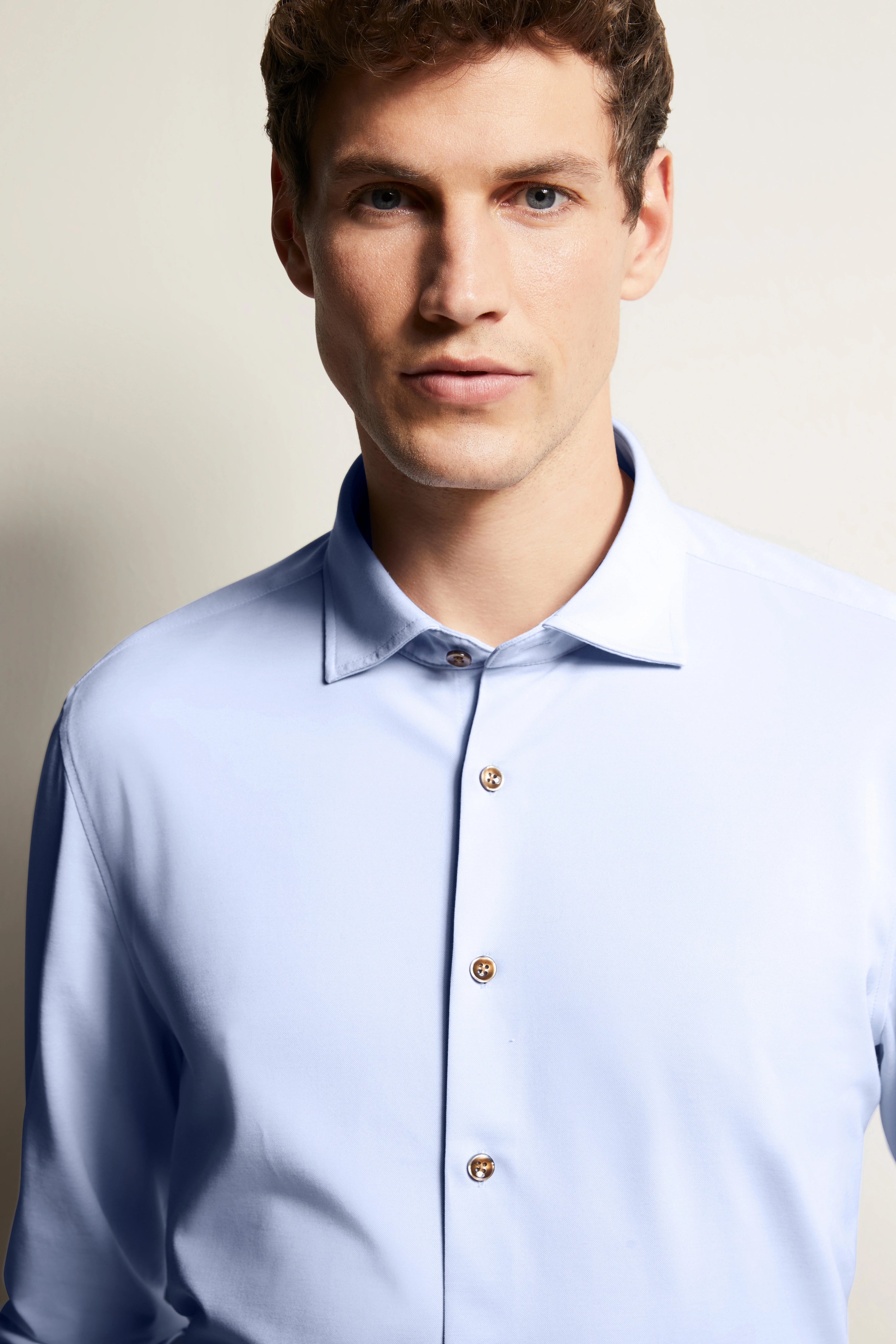 Bügelbild von bugatti: Hellblaues Hemd mit Knöpfen, Model frontal, entspannter Ausdruck.
