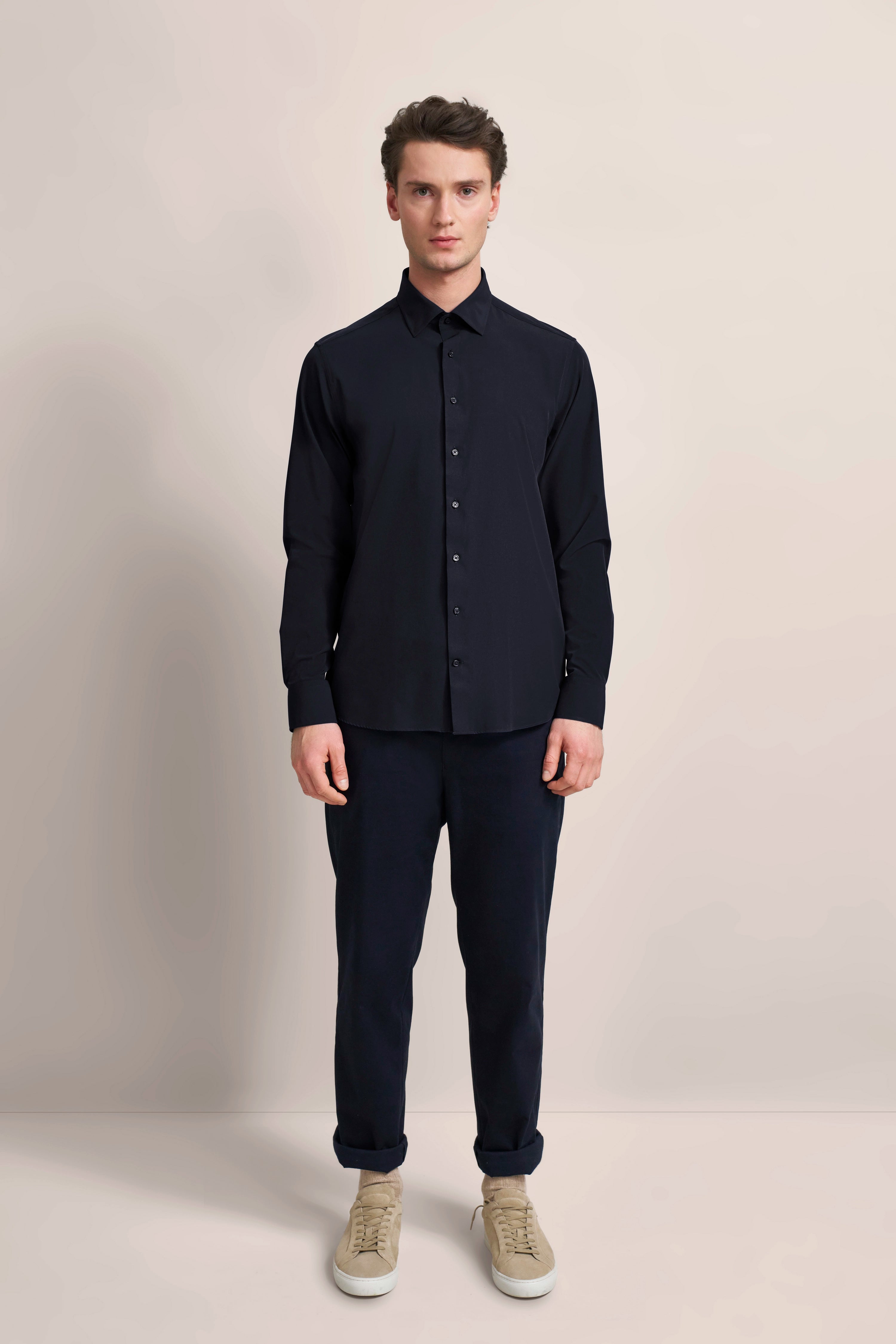 Model in dunkelblauem bugatti-Hemd und Hose, beigefarbene Sneaker, frontal stehend.