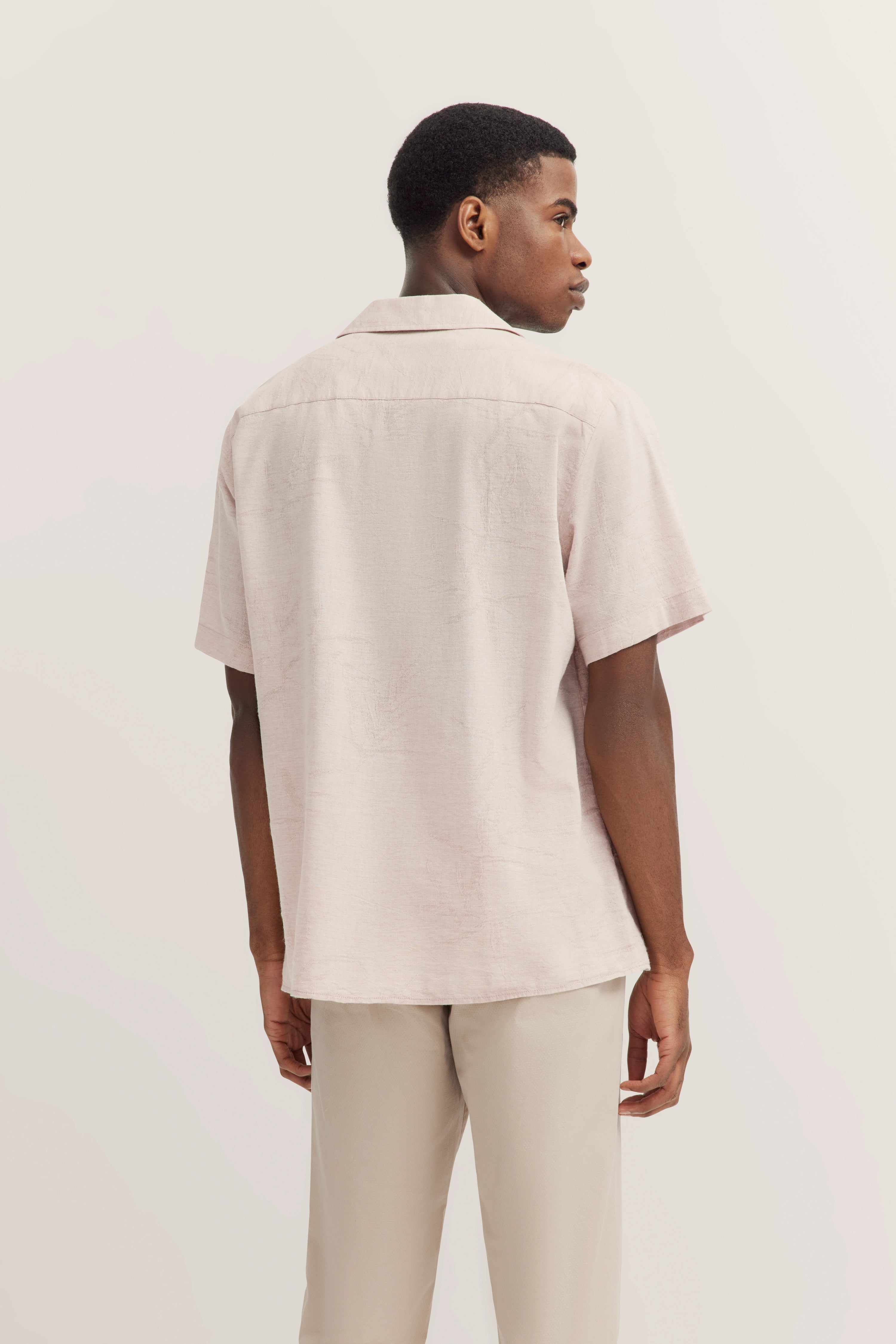 bugatti Hemd beige, kurzärmelig, Rückansicht auf Model in legerer Pose, kombiniert mit heller Hose.