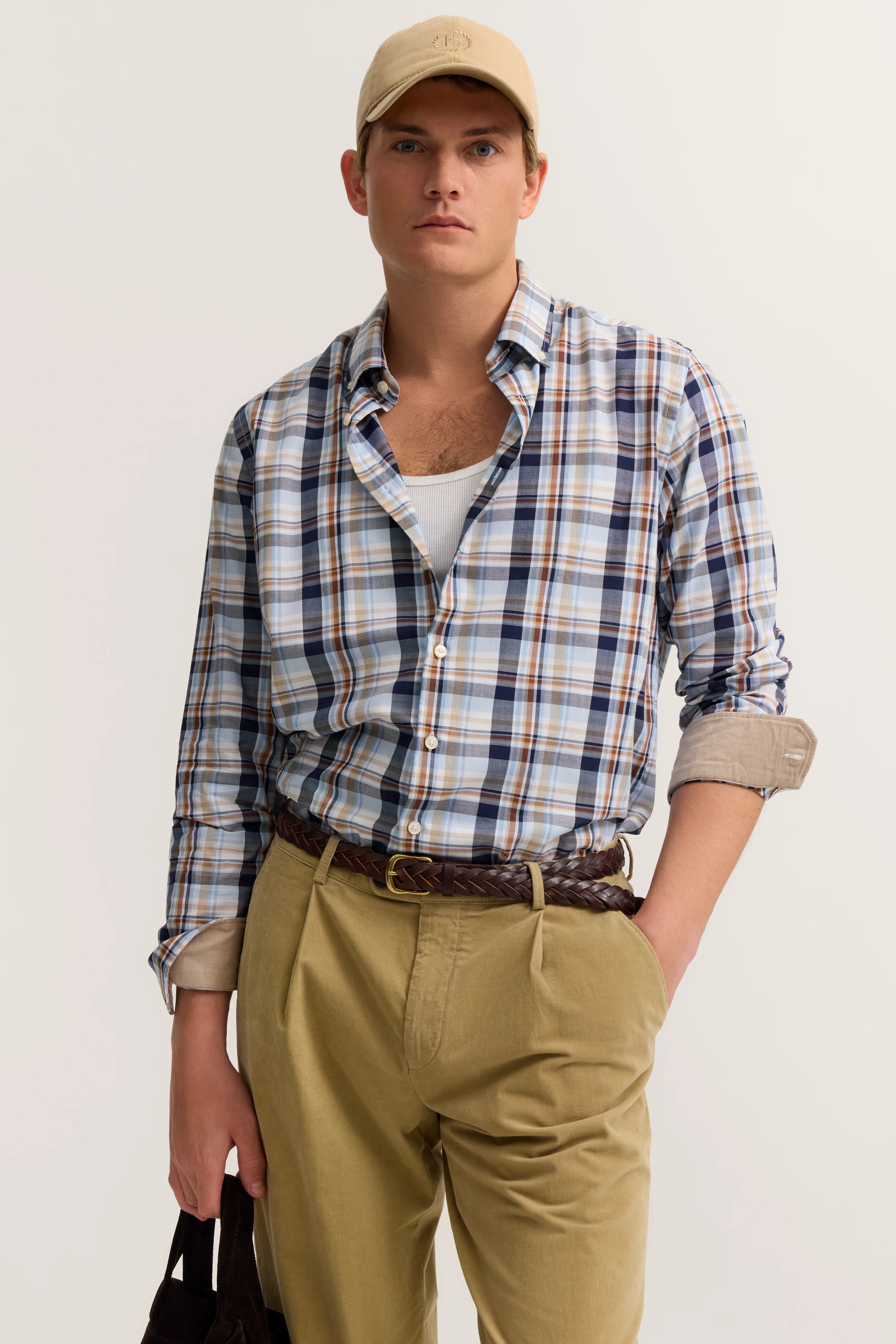 Model in beiger Kappe, kariertem Hemd, weißem Shirt, beigen Hosen