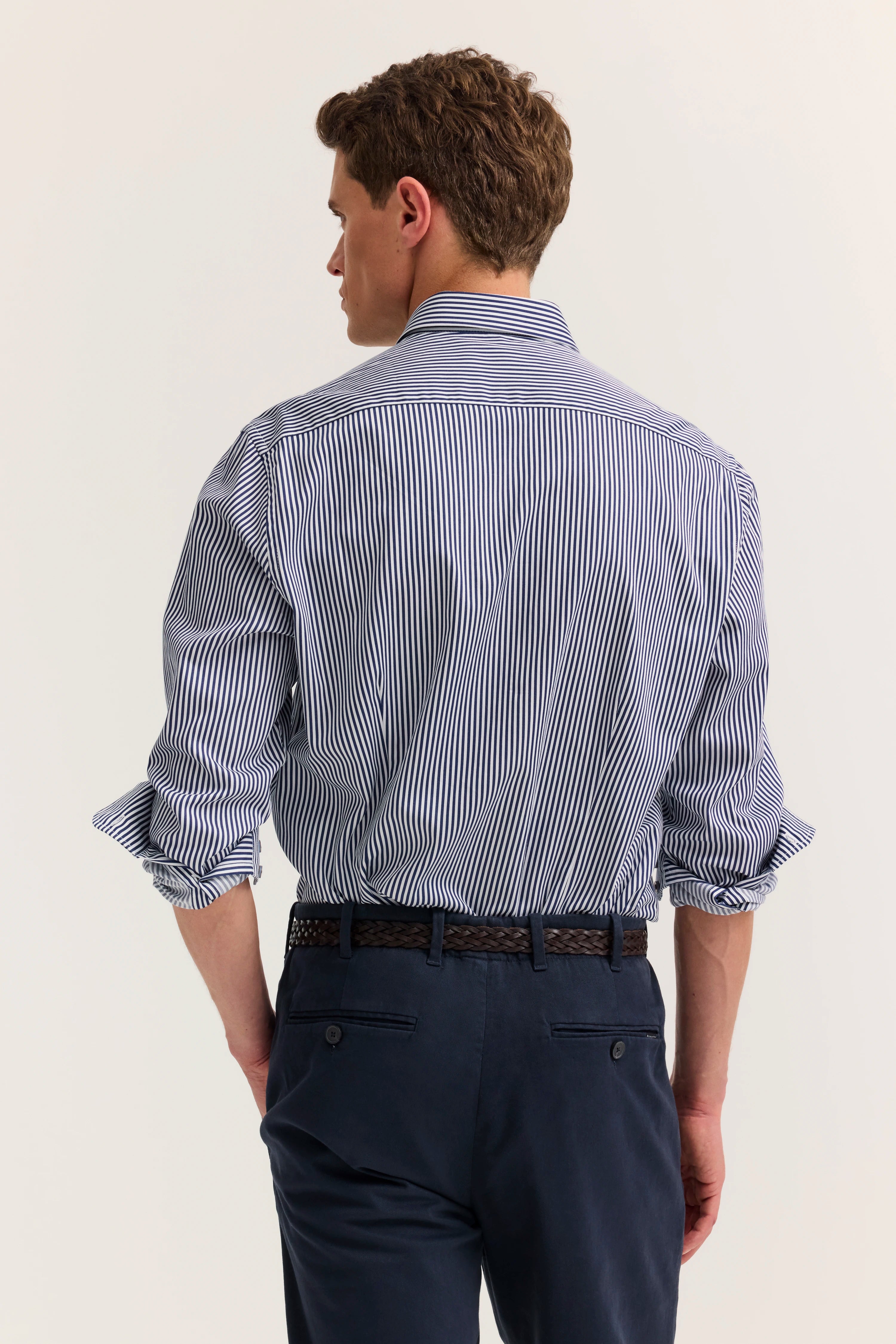Herrenoutfit: gestreiftes Hemd, hochgekrempelt, mit navy Chinos. Model von hinten.