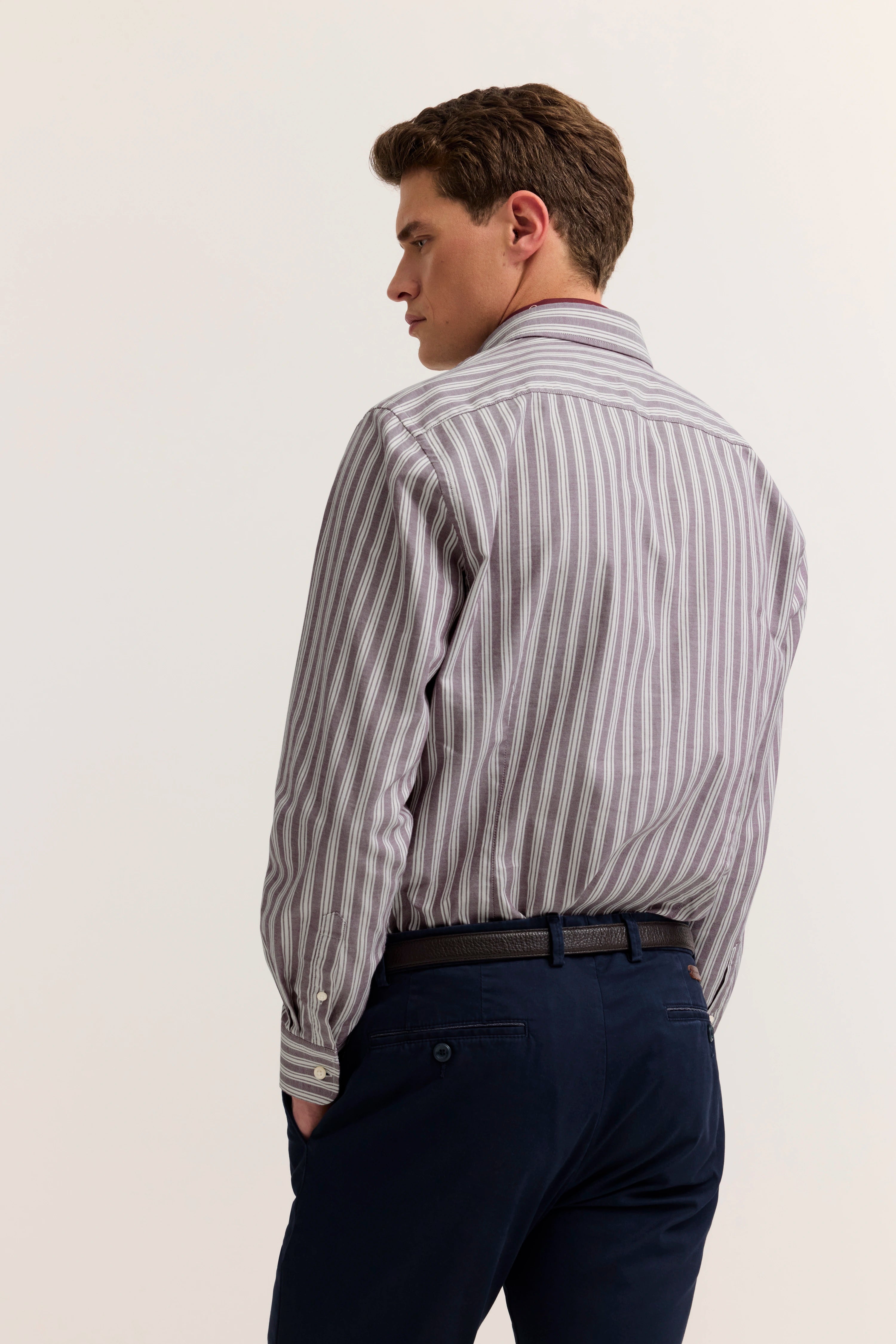 Bugatti Hemd mit lila Streifen, dunkelblaue Hose, Model von hinten, lässige Pose.