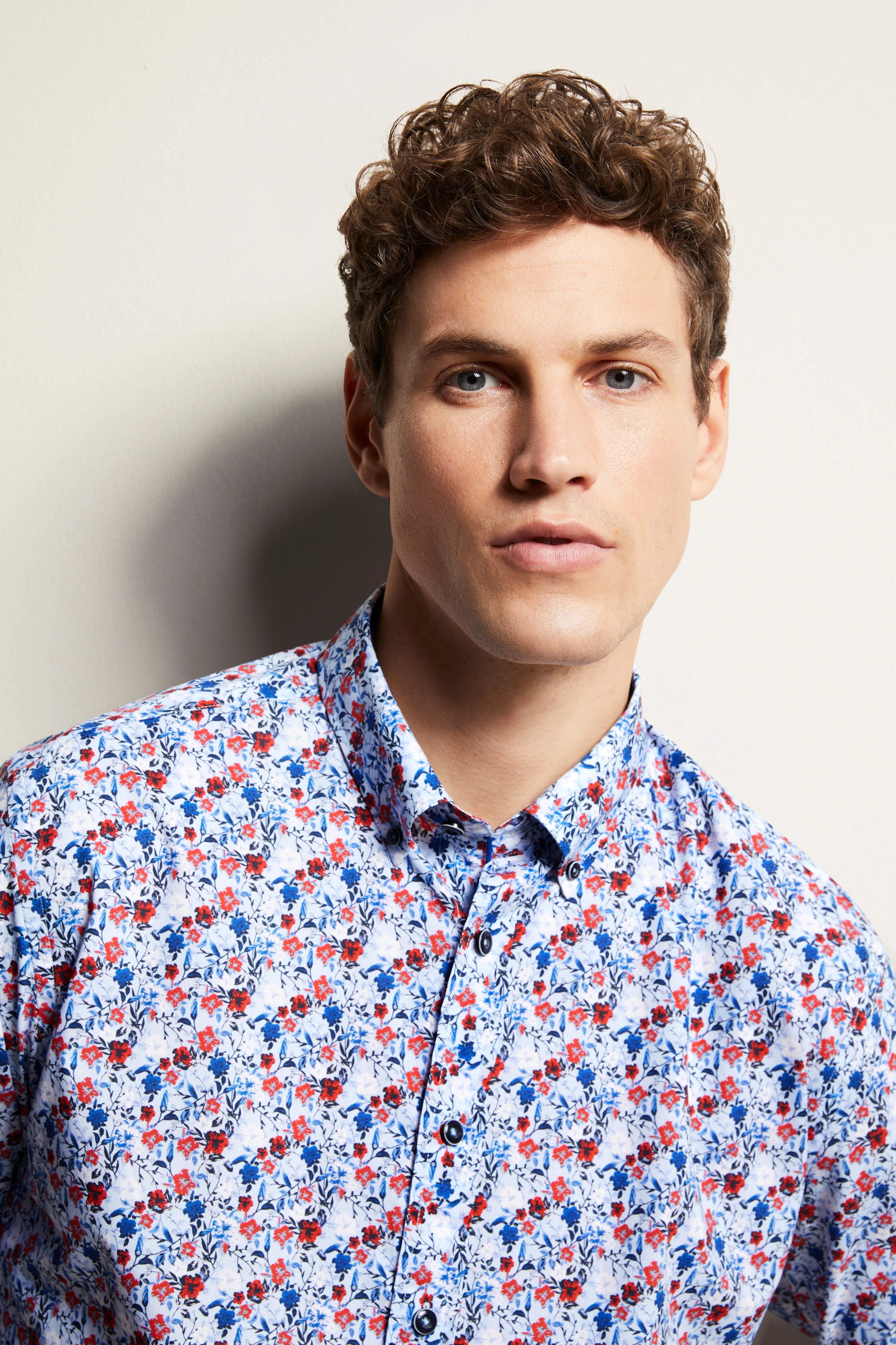 Model close-up, floral shirt in blue-red-white, casual look.