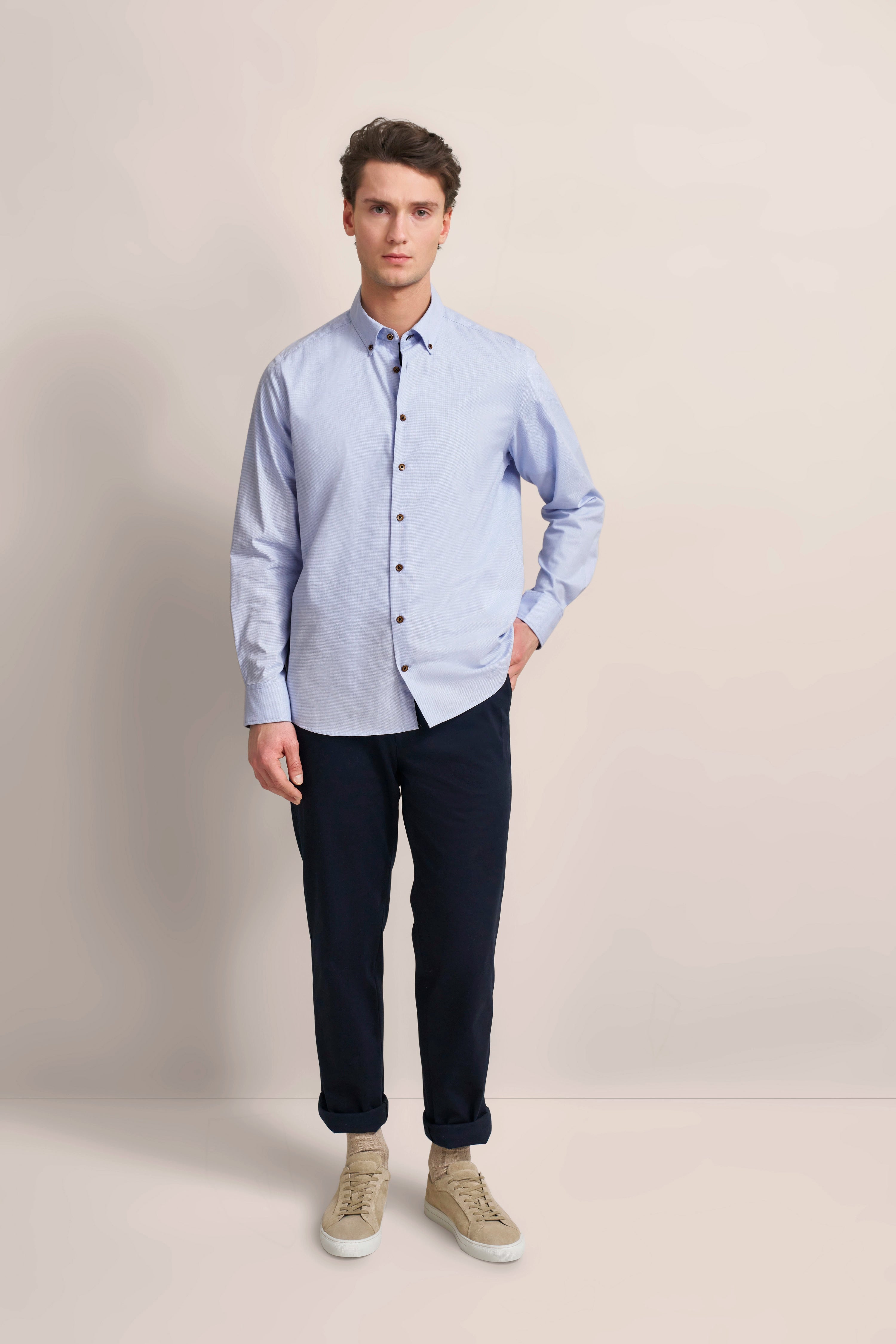 Blue shirt, dark blue pants, beige sneakers, model posing, relaxed elegance.