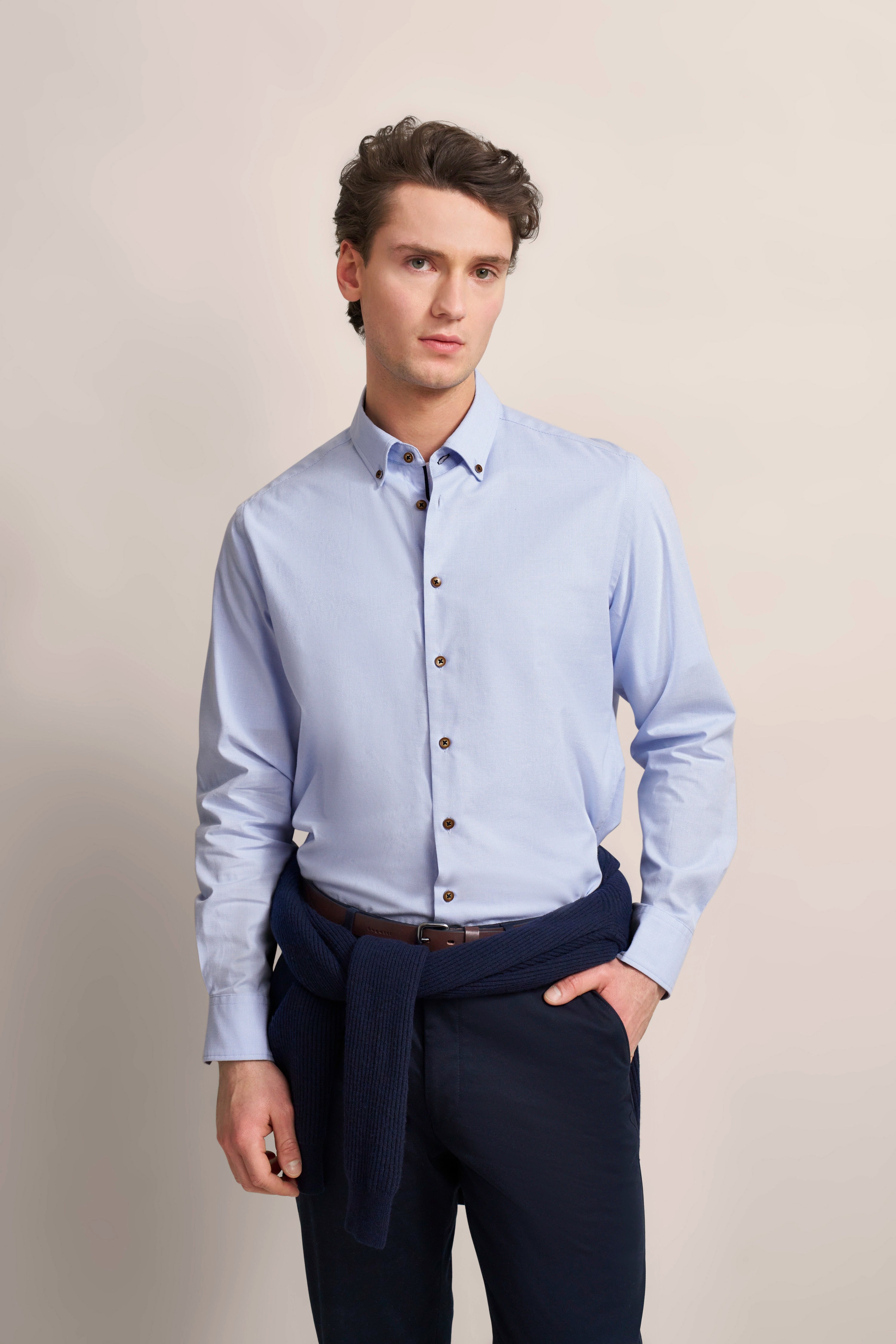 bugatti model in light blue shirt, dark blue sweater tied at waist, casual pose.