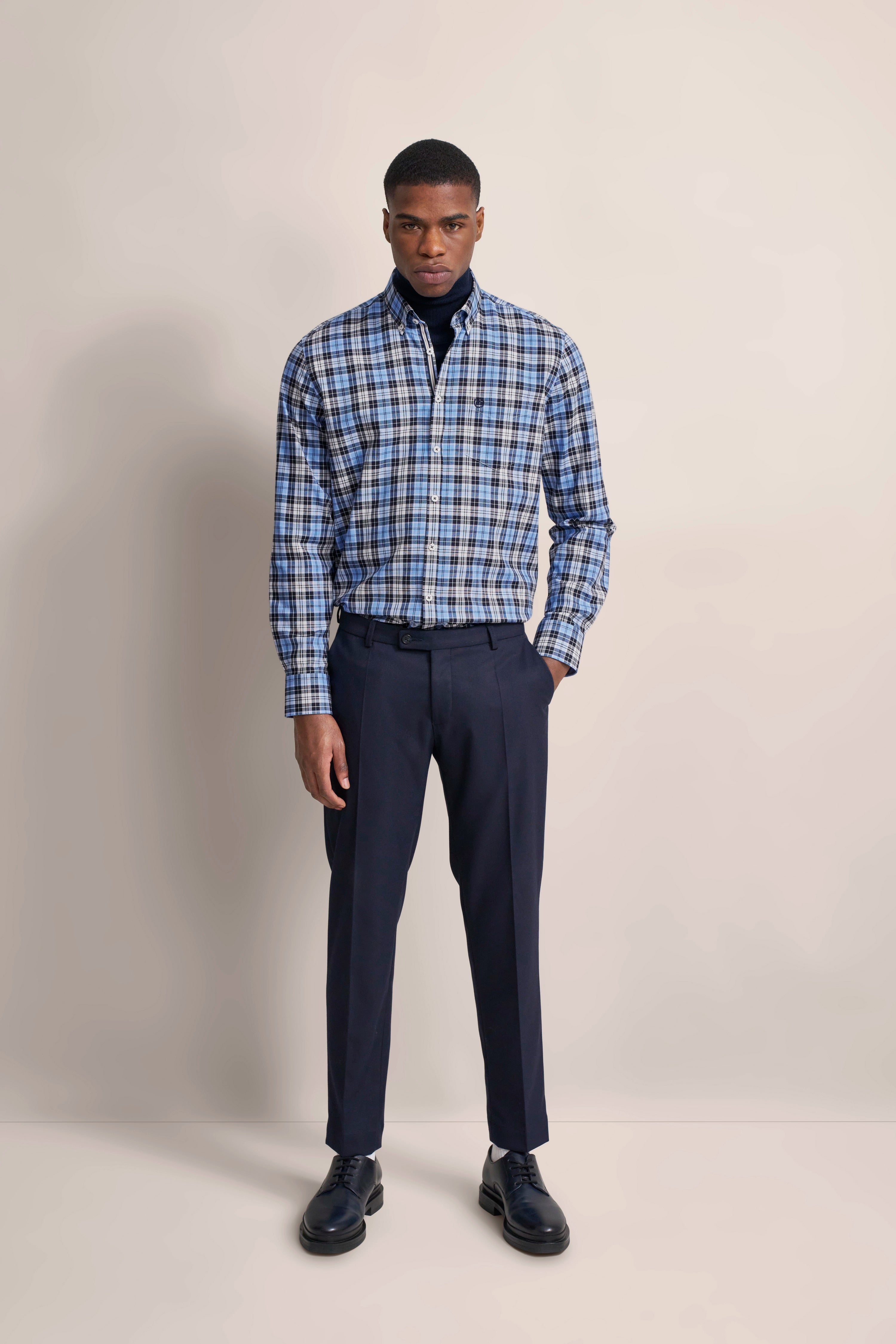 bugatti model in blue checkered shirt, dark blue pants, casual pose, stylish look.