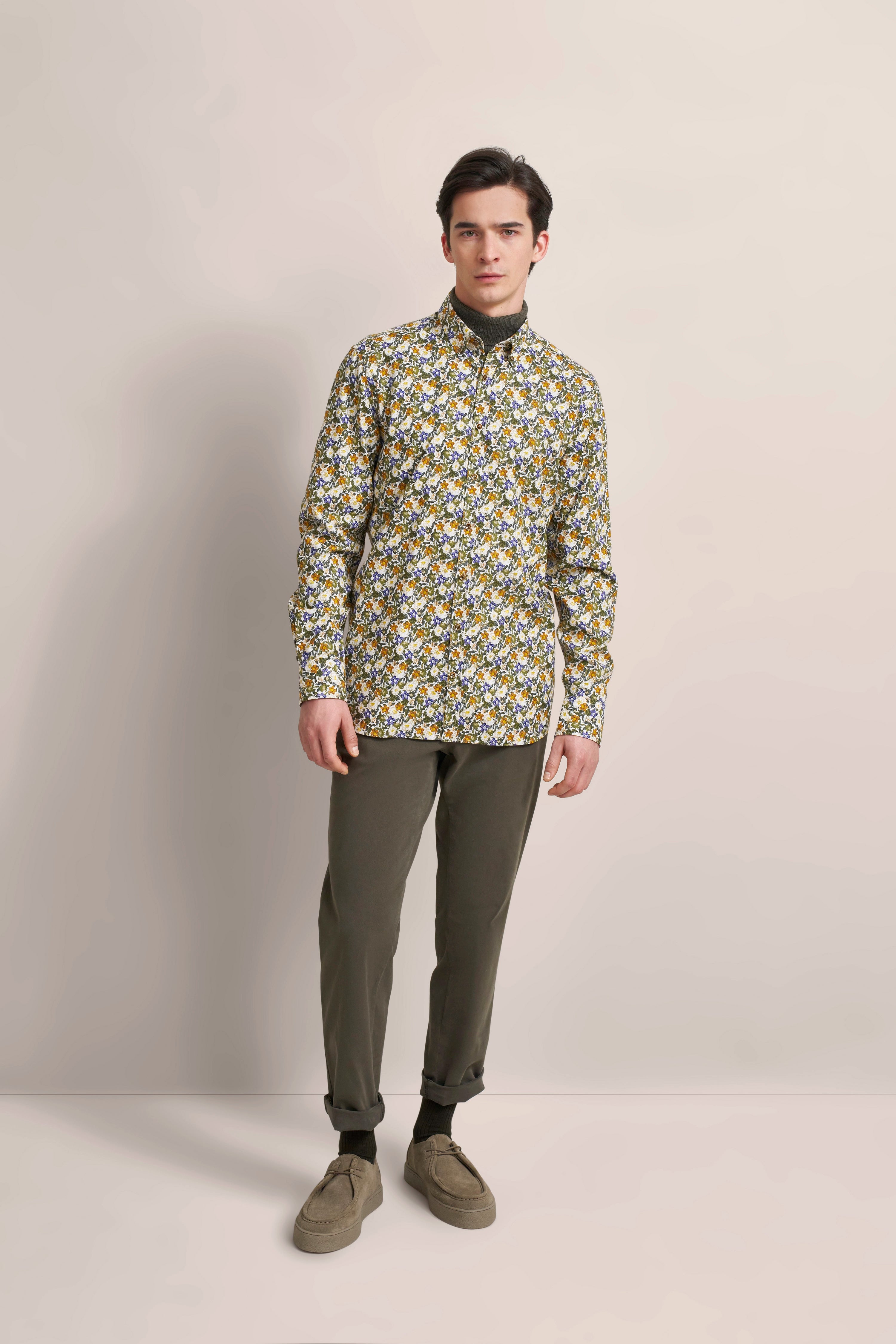 Model in gemustertem Hemd, olivgrüner Hose, lässigem Stand. Elegantes bugatti Outfit.