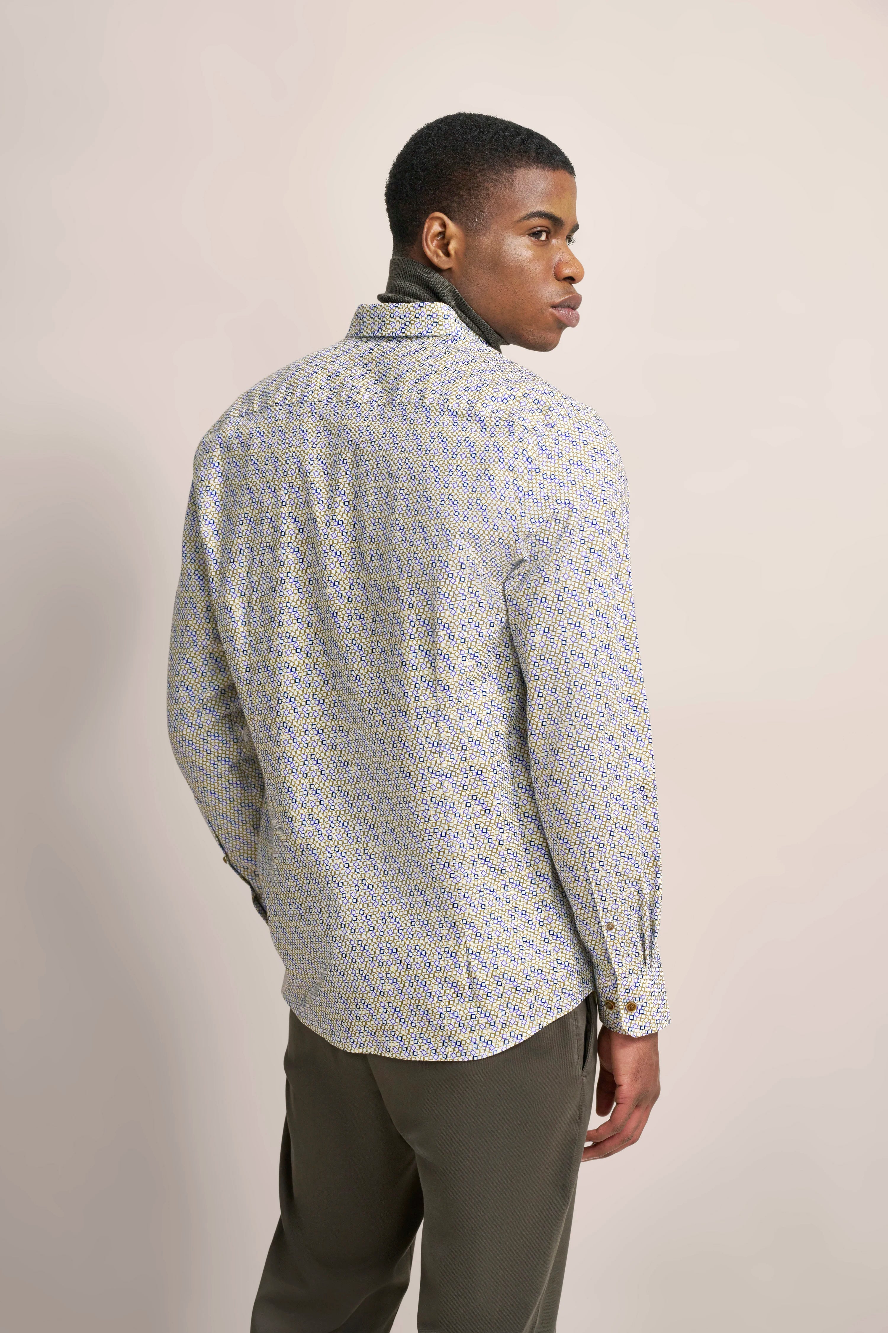 Model im gemusterten bugatti Hemd, Rückenansicht, legeres Posing, kombiniert mit olivgrüner Hose.