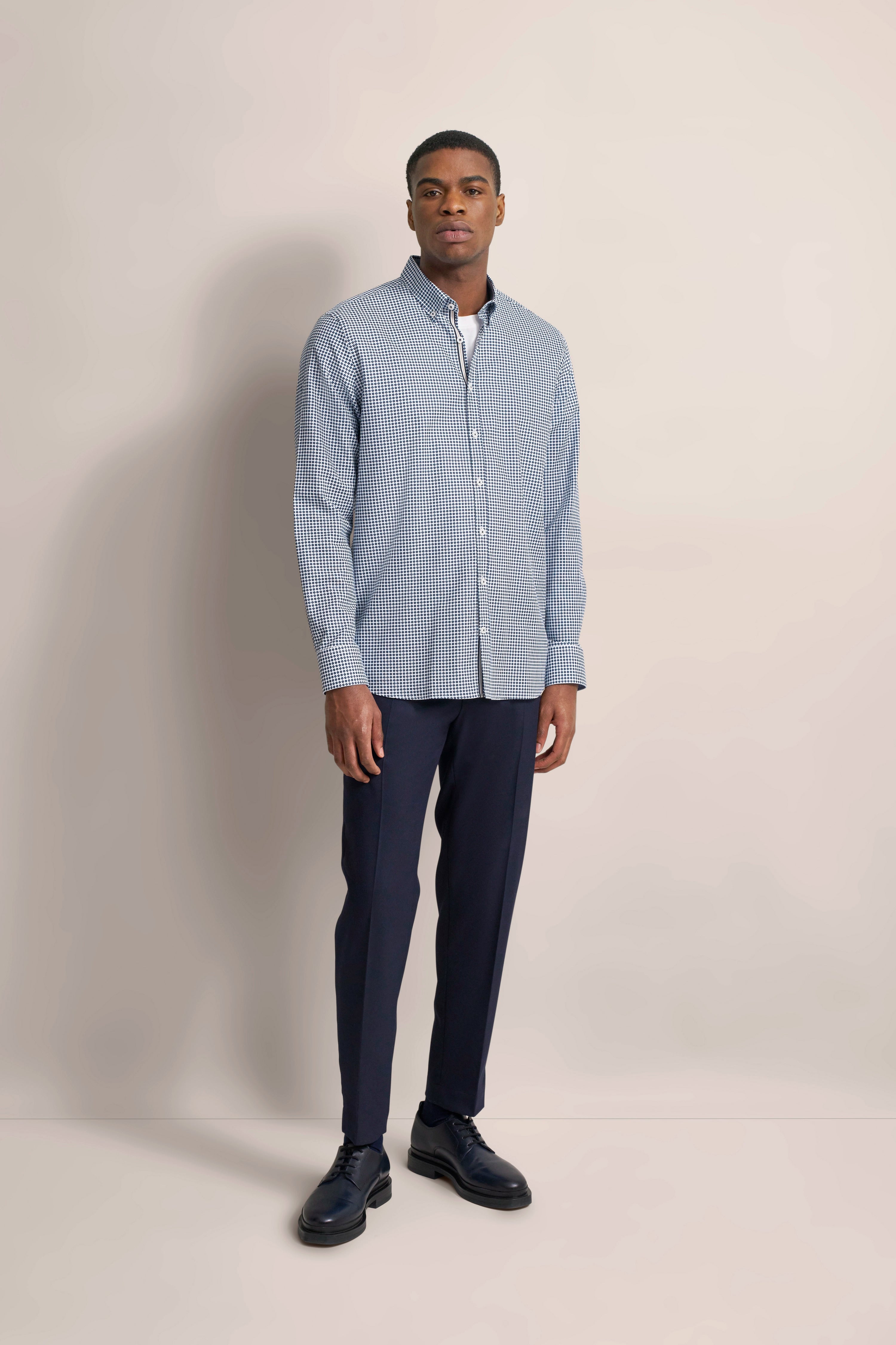 Blue checkered shirt and dark blue pants, model in relaxed pose, bugatti style.
