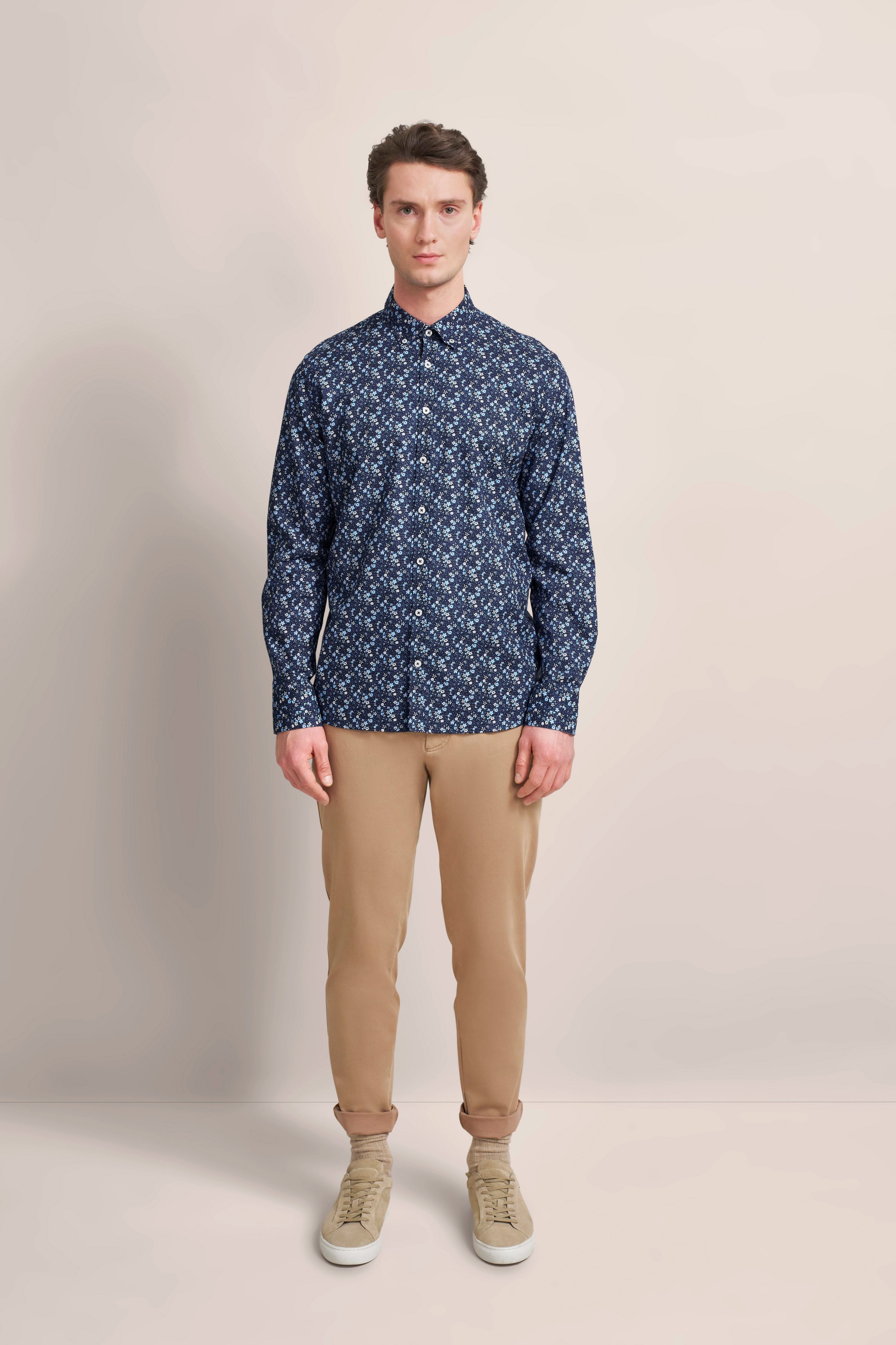 bugatti Modell in gemustertem, blauem Hemd und beigen Chinos, steht frontal, entspannter Look.