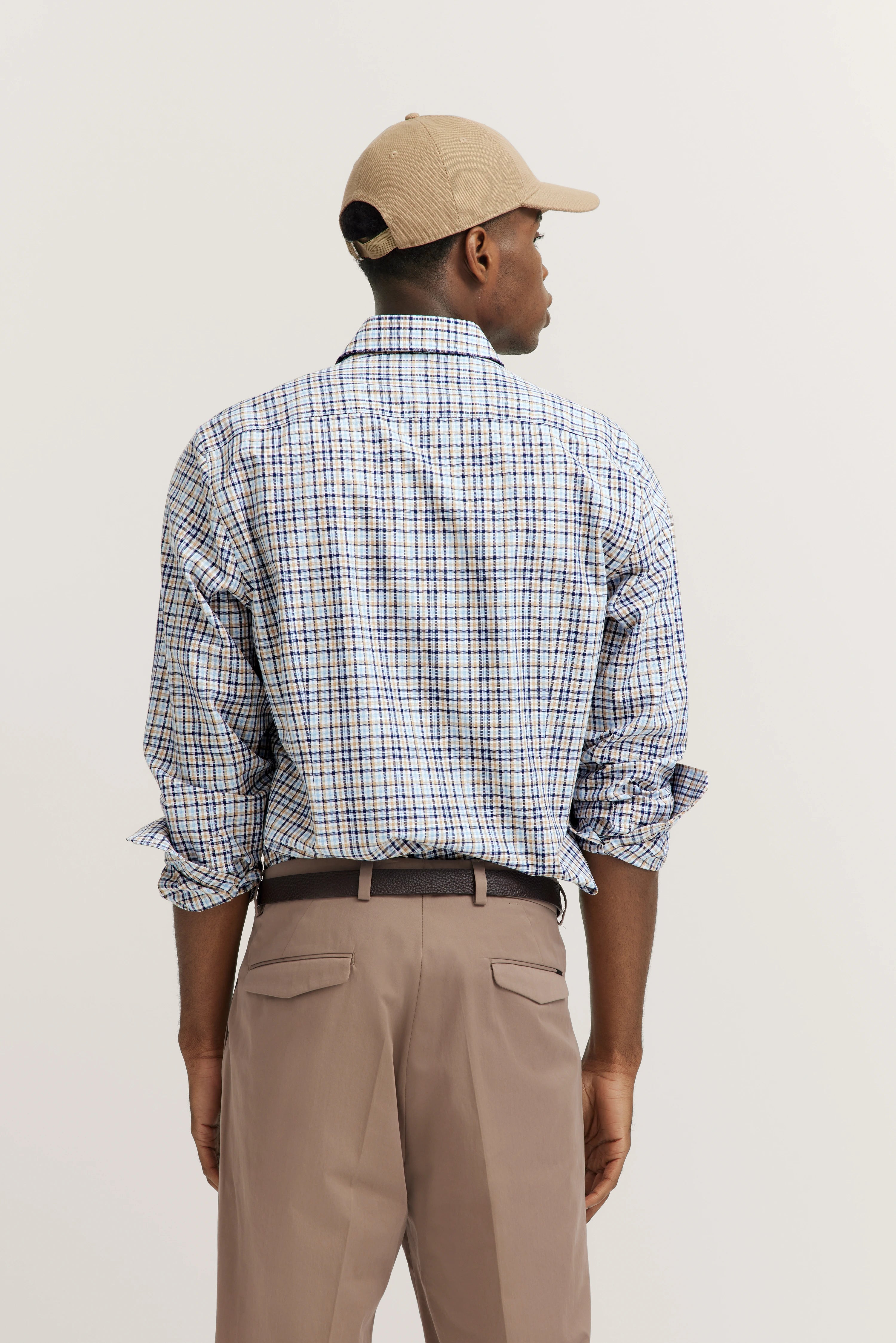 Man in geruit overhemd en beige broek van achteren, casual modelbeeld.
