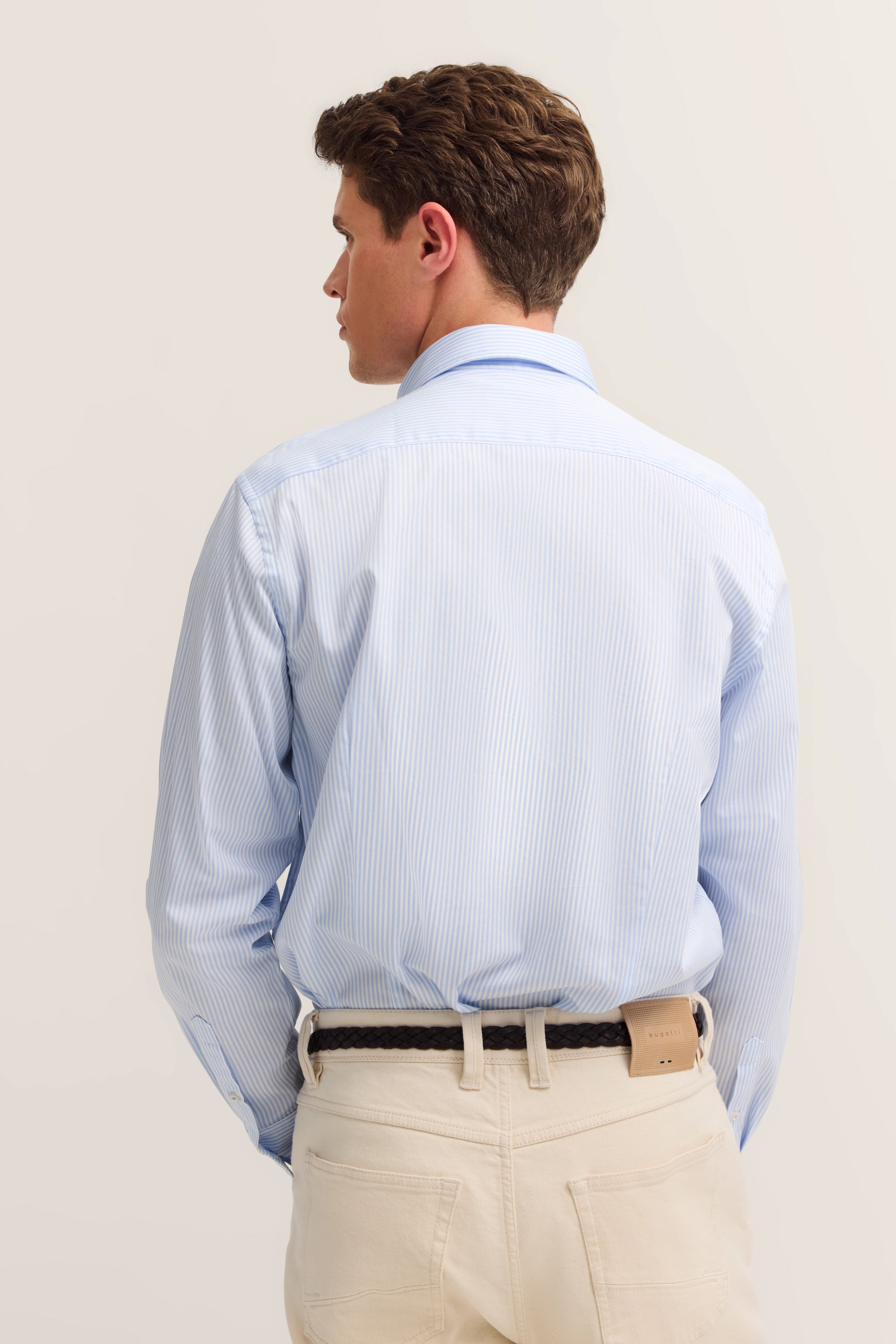 Blauw-wit gestreept overhemd, beige broek, model van achteren, ontspannen pose, bugatti stijl.