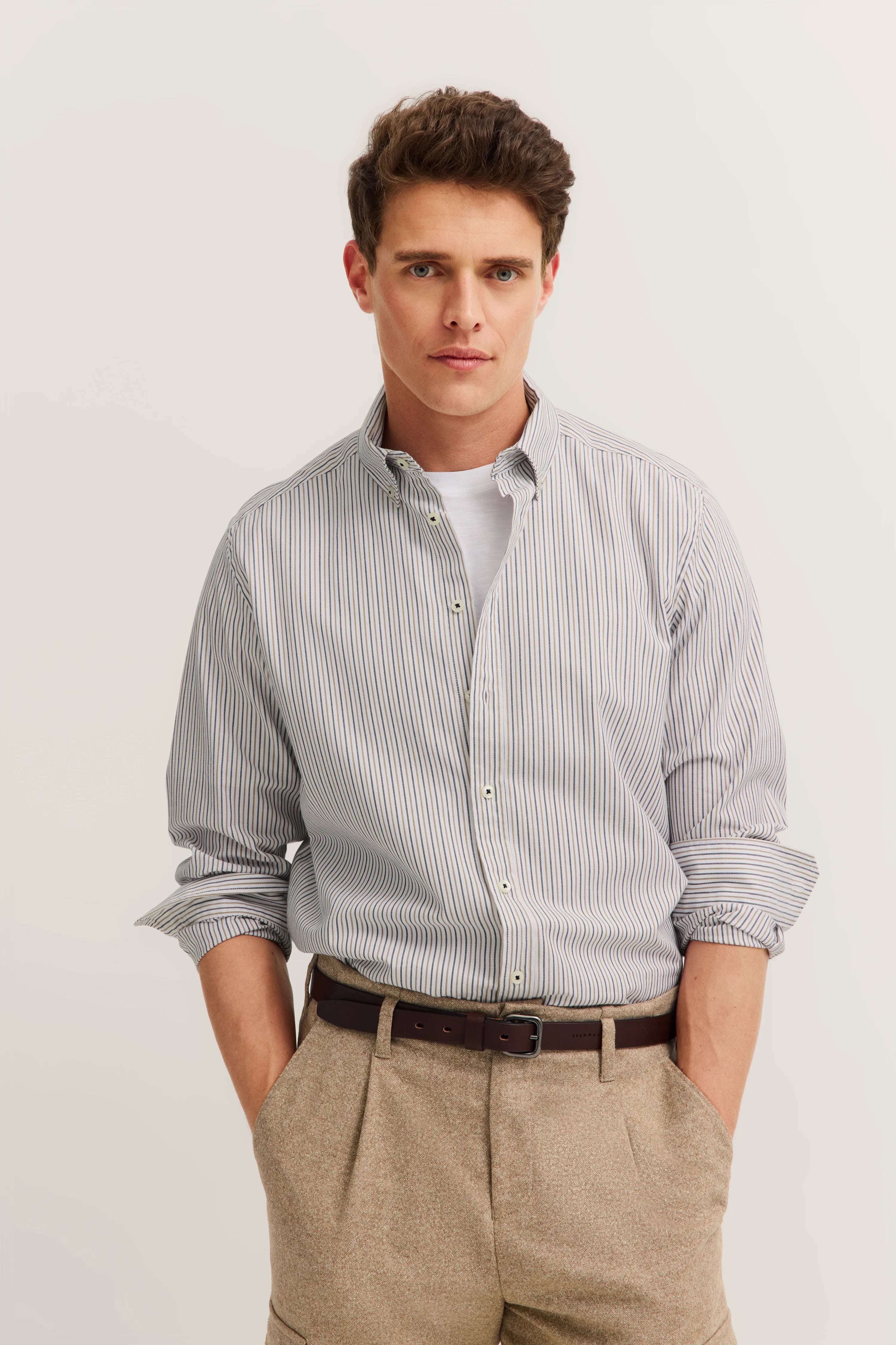 Bust portrait: Man in striped shirt and beige trousers by bugatti, relaxed pose.