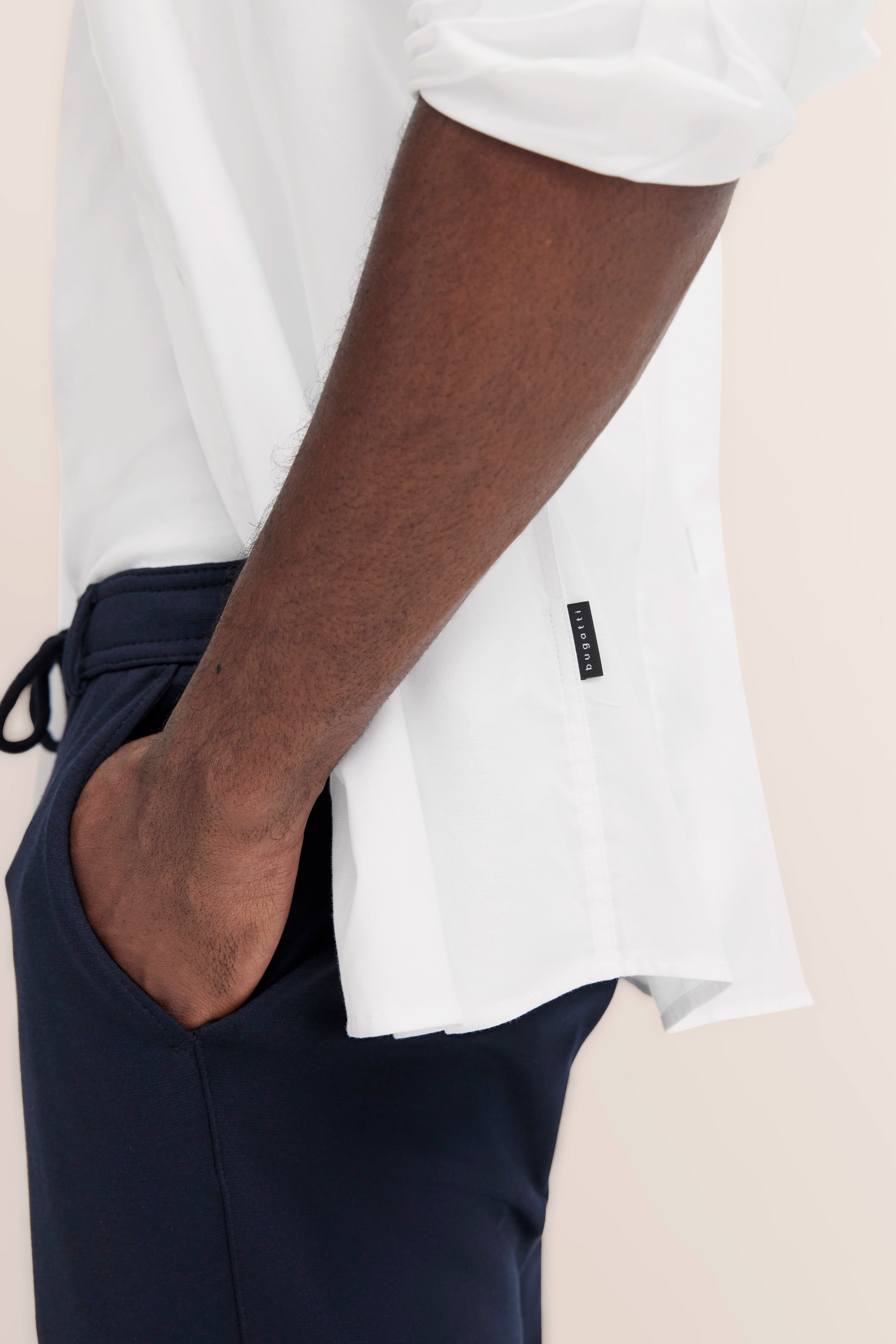 Weiße bugatti-Hemdärmel und dunkelblaue Hose, legeres Modelbild mit Hand in Hosentasche.