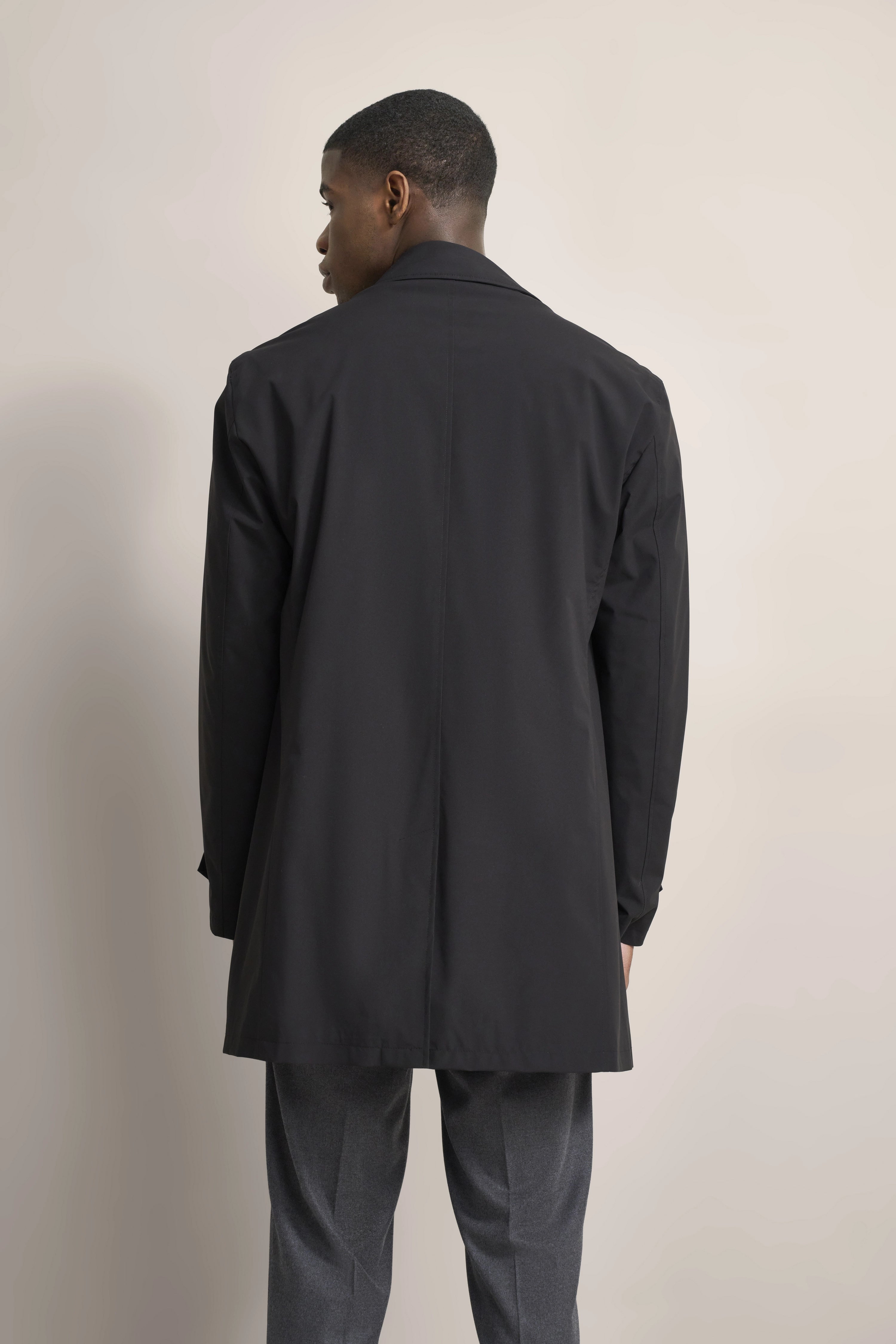 bugatti coat in black, back view, casual pose, paired with gray pants.