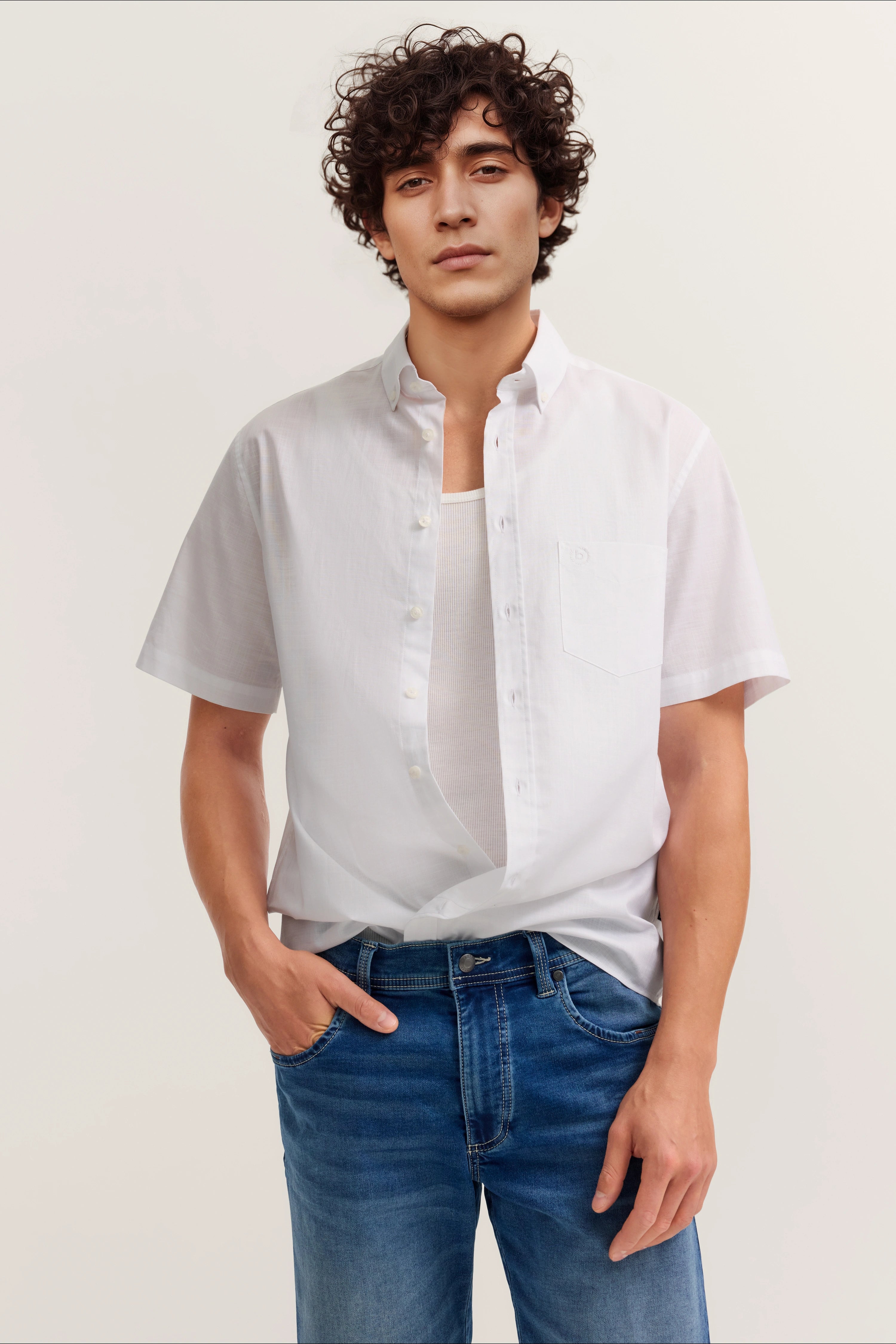 Weißes Hemd und blaue Jeans, lässiges Modelbild, entspannte Pose.
