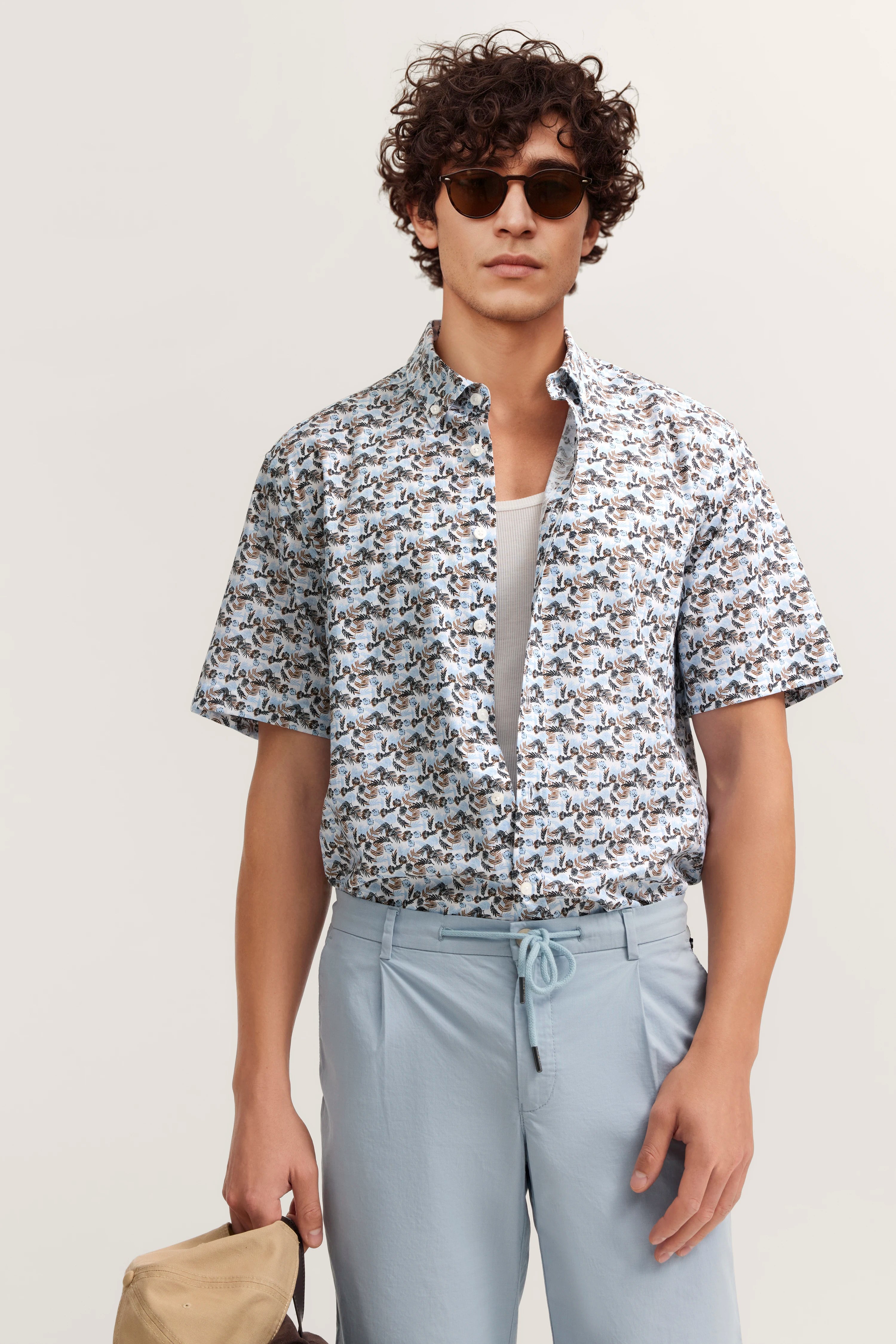 Kurzärmeliges gemustertes Hemd und hellblaue Hose, Modelbild mit entspannter Pose.