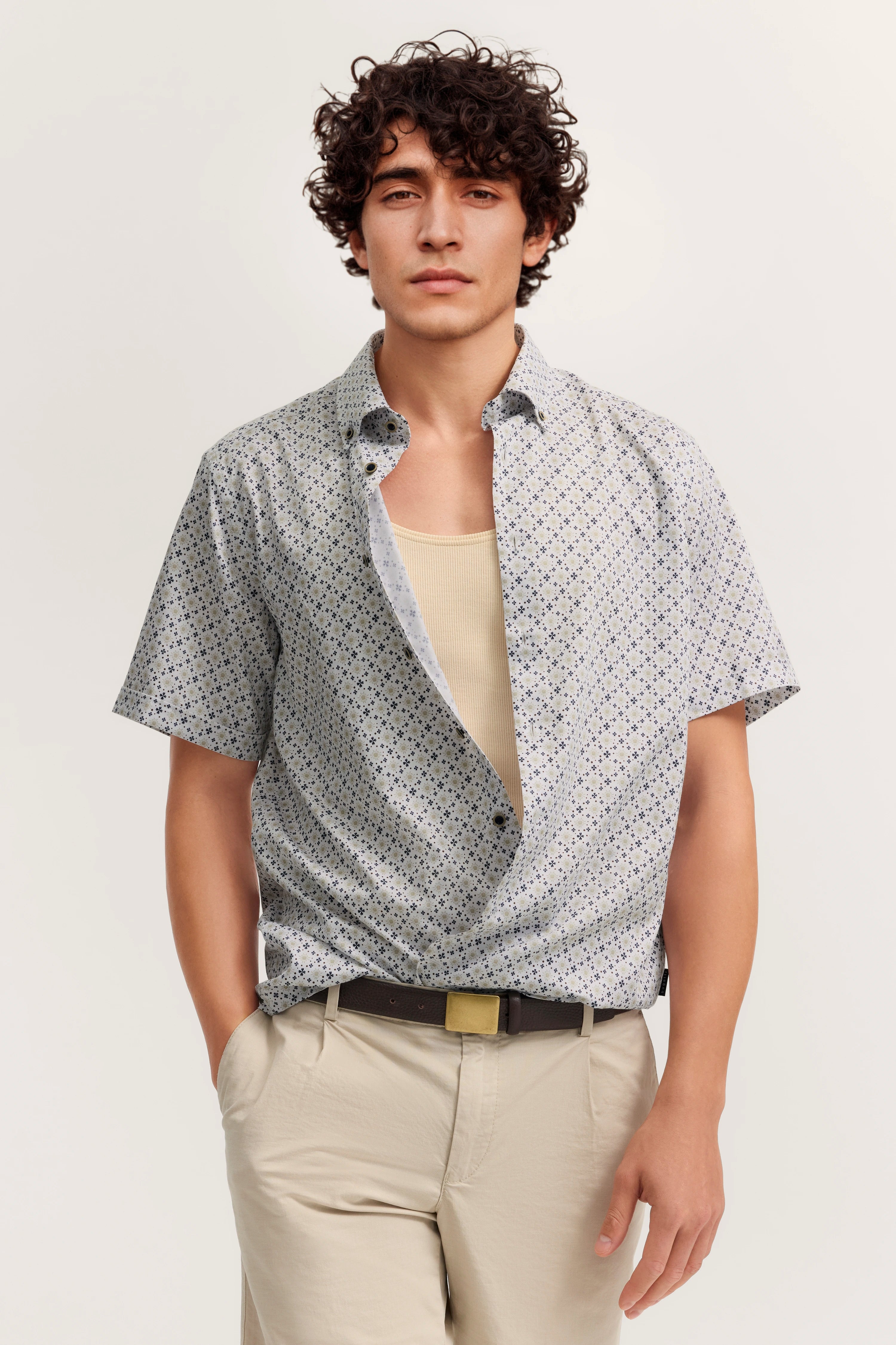 Kurzarmhemd mit Muster, hellbeige Hose, Model lässig stehend, Hände in Taschen, bugatti Stil.