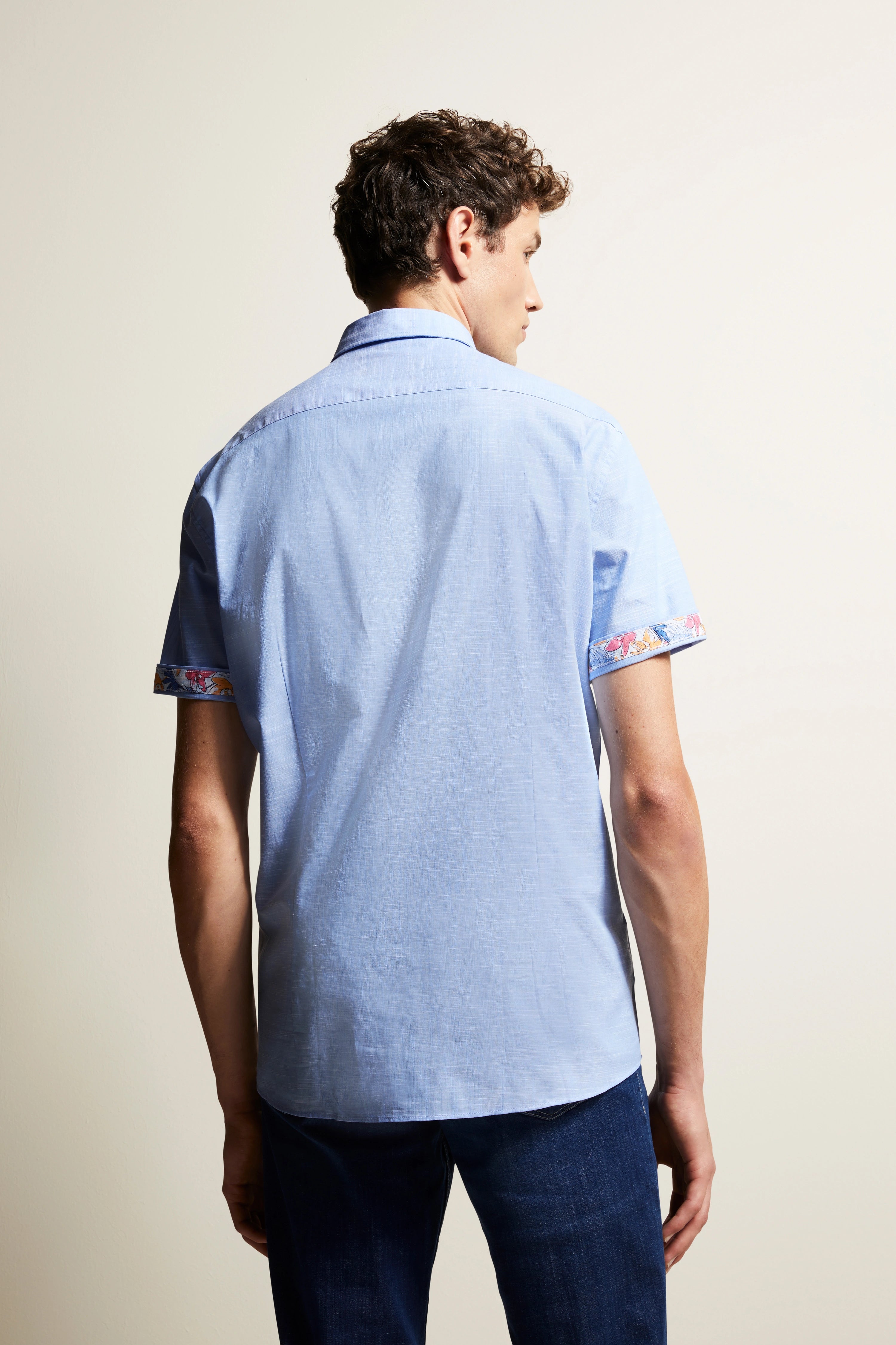 Blaues Hemd mit gemusterten Ärmeln, Rückansicht auf Model, lässige Pose.